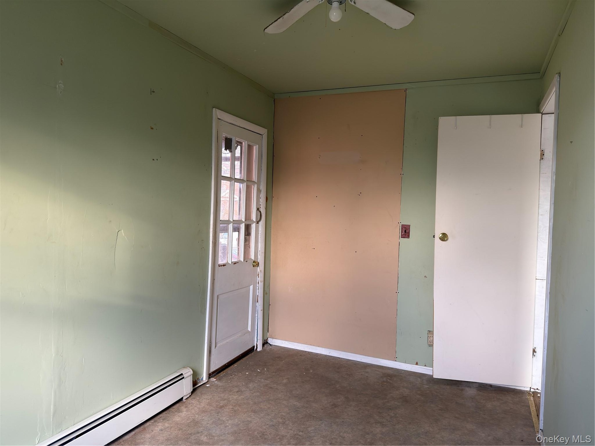 Unfurnished bedroom with a baseboard heating unit, ceiling fan, and concrete floors