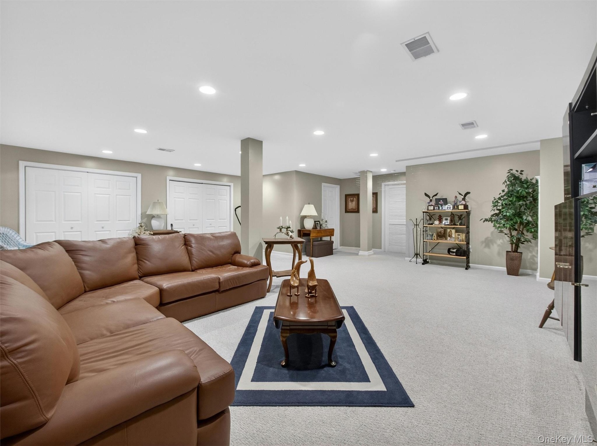 Another basement view featuring two large double closets, a fully finished bathroom with shower stall, and door leading to the utility room with addit
