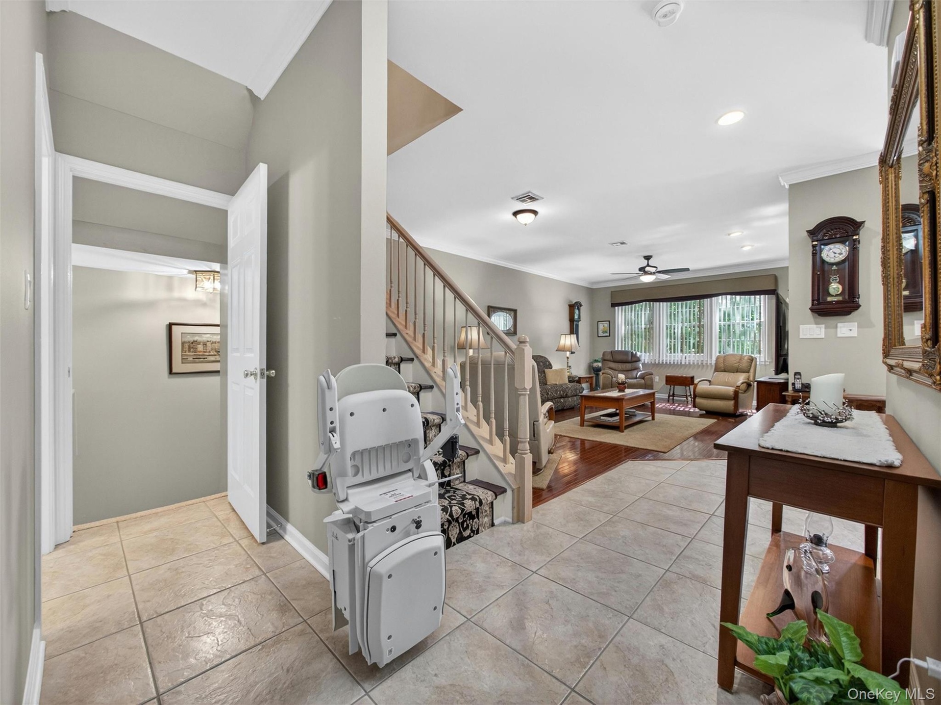 View from the entry foyer thru to the living room and basement entrance to the left. Chairlift only recently installed; can be removed if buyer prefer