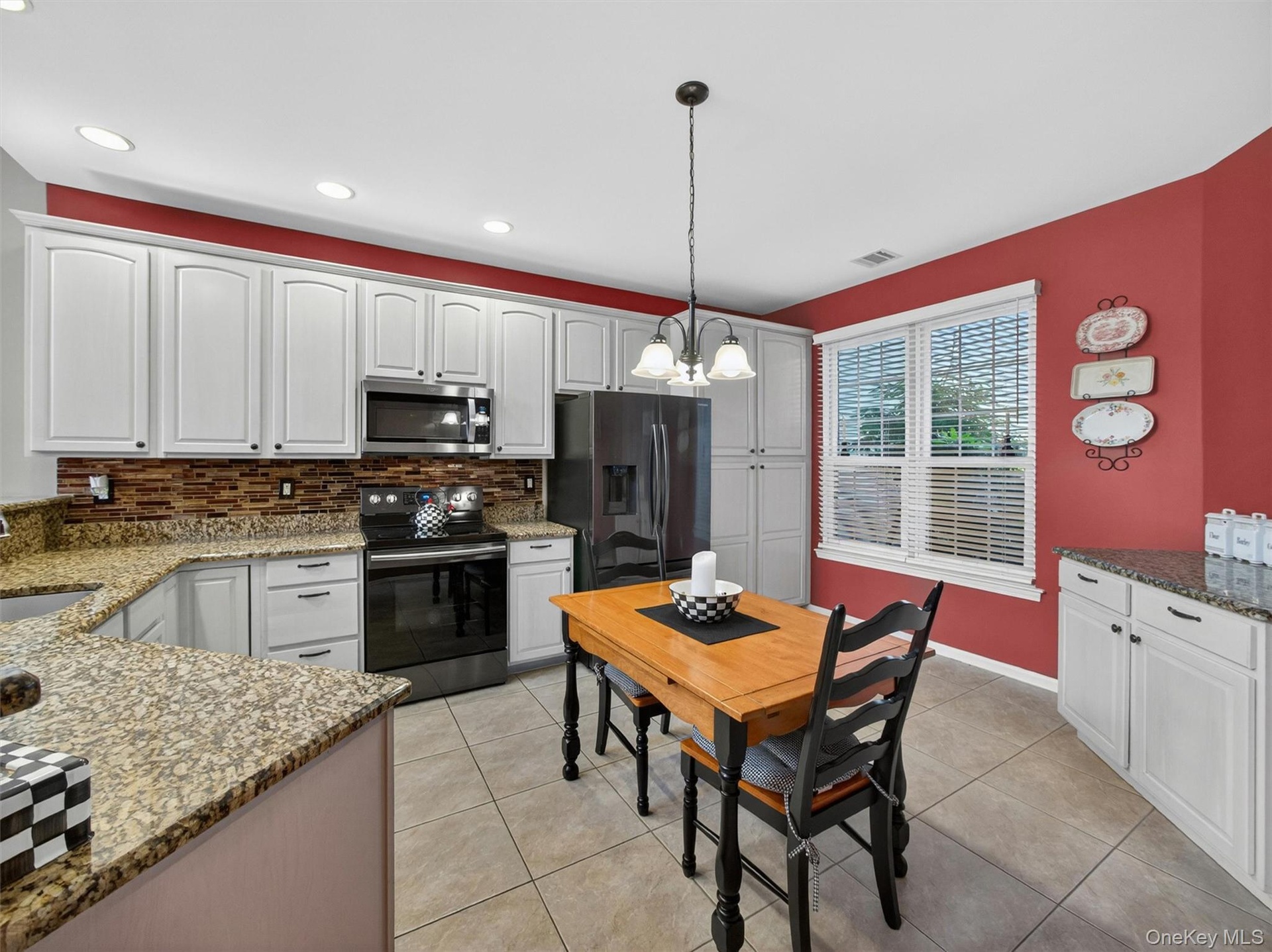 Generous cabinetry and counterspace with a double-window overlooking the professionally landscaped cobblestone walkway.