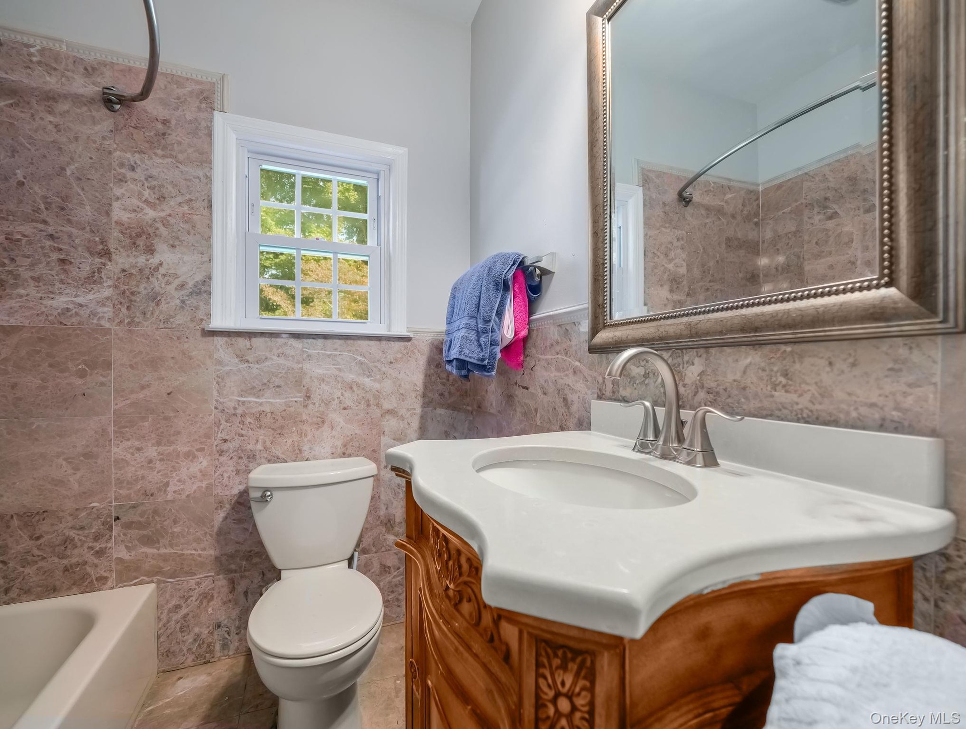 Bathroom featuring vanity, tub / shower combination, wainscoting, and tile walls
