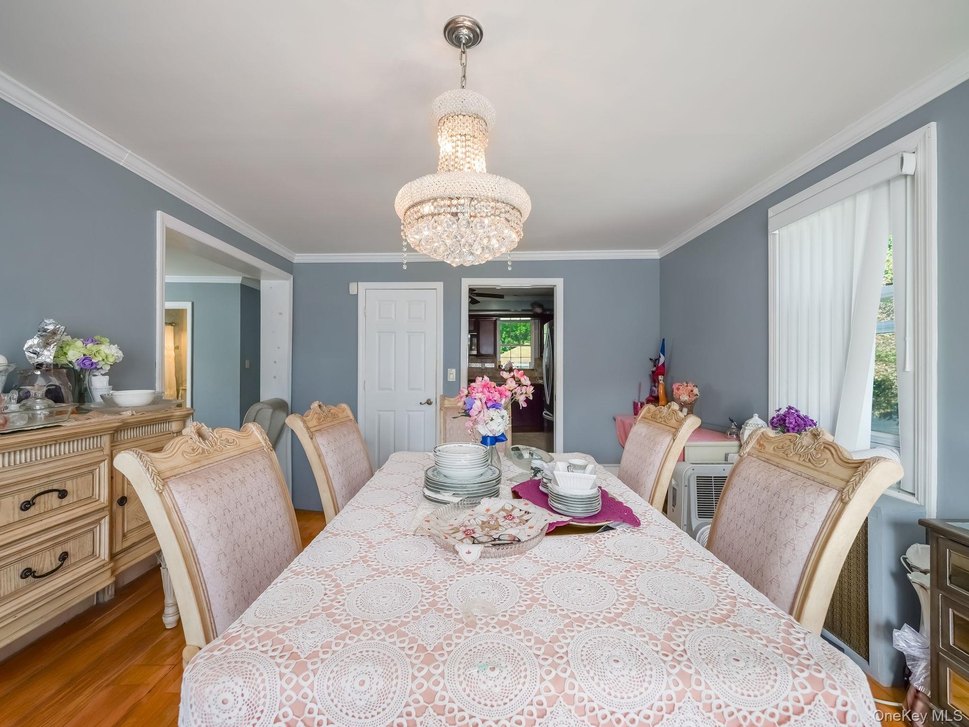 Dining area with a chandelier, wood finished floors, and crown molding