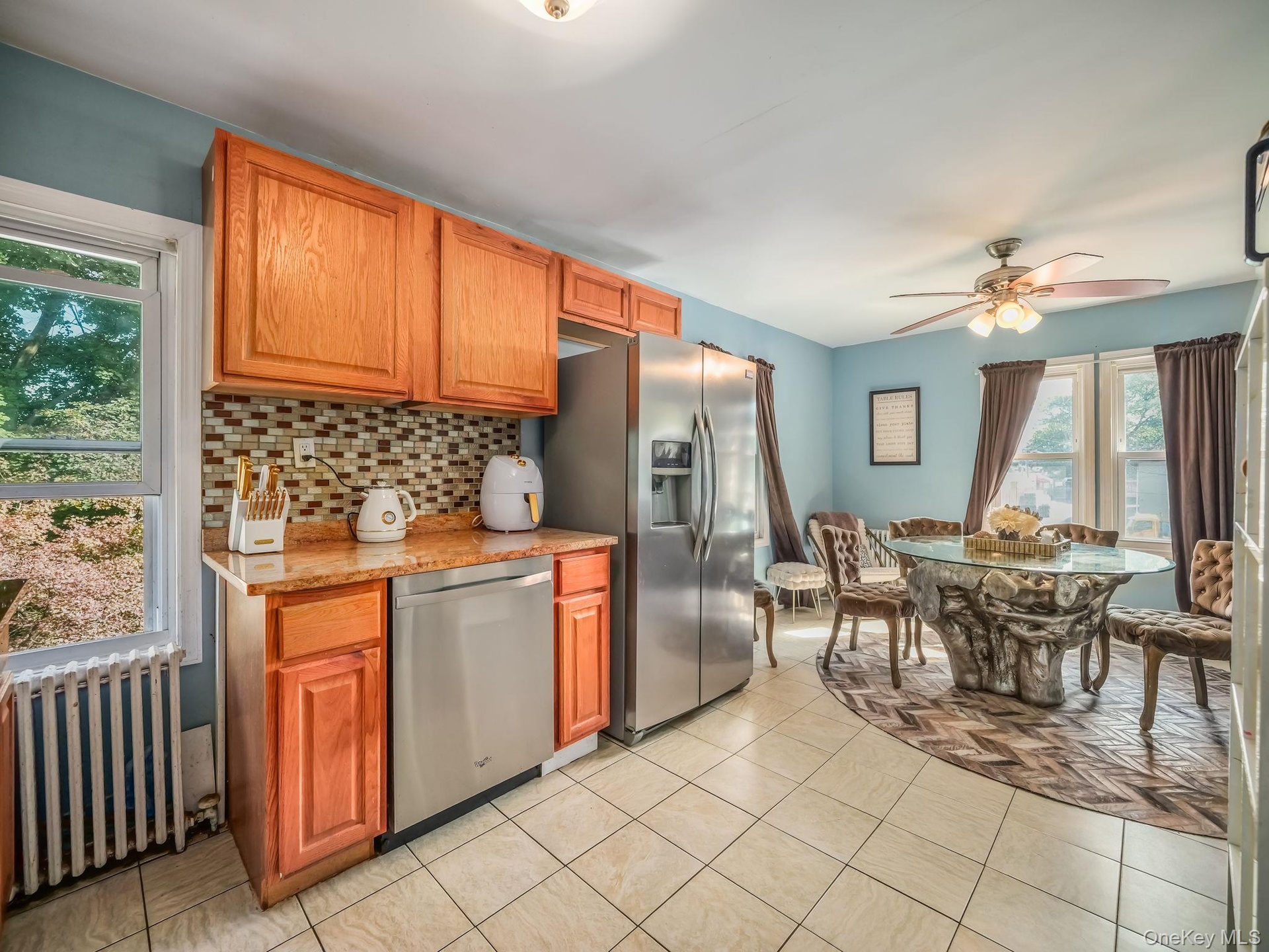 Kitchen featuring radiator heating unit, stainless steel appliances, backsplash, and brown cabinetry