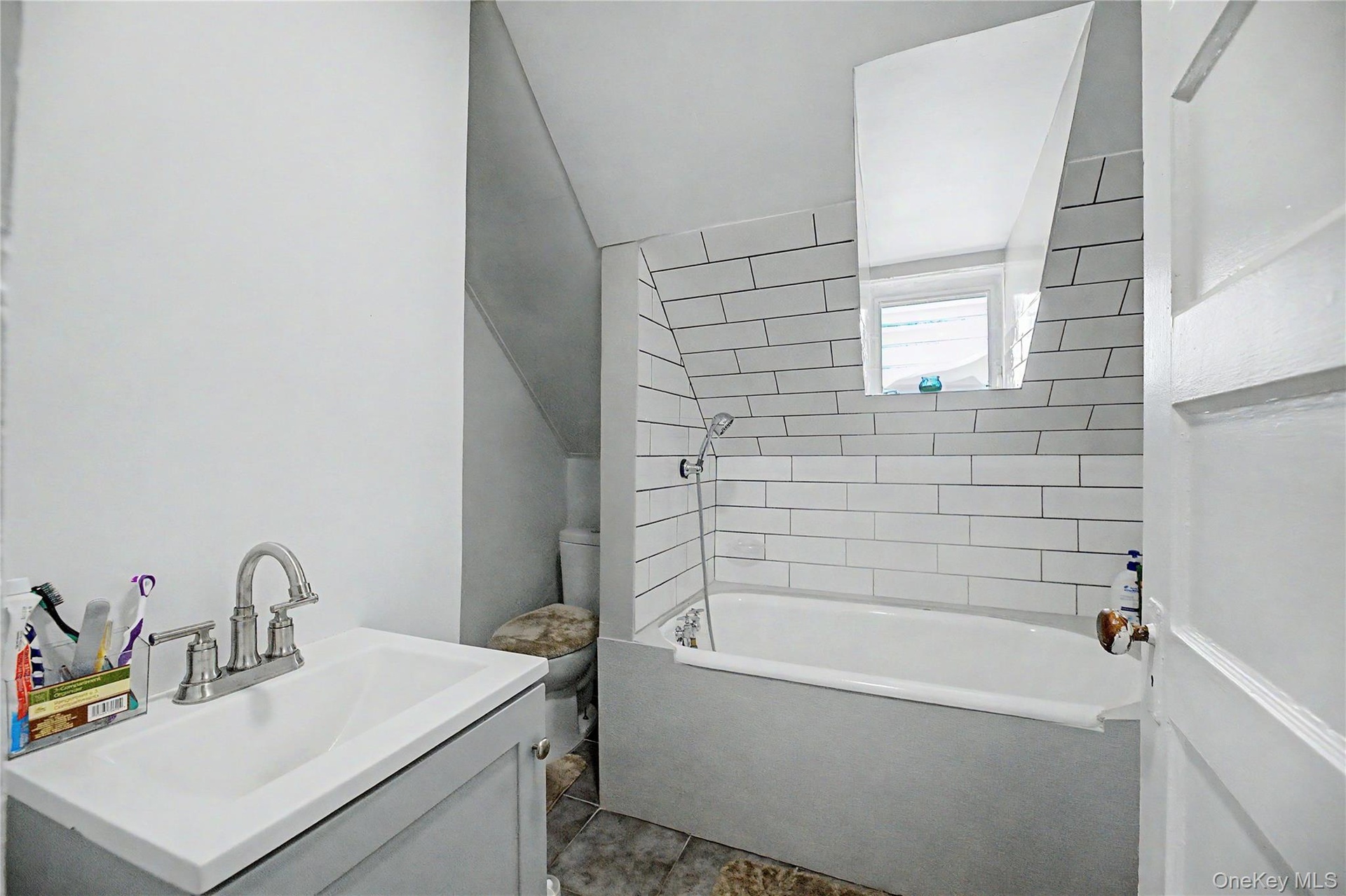 Bathroom featuring a white subway tile surround, built-in bathtub, and a vanity with a brushed nickel faucet