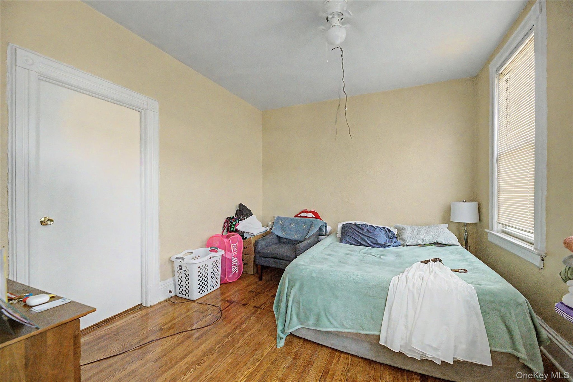 Sloped ceiling room featuring wood-finish flooring, a double window, and a flush-mount light fixture