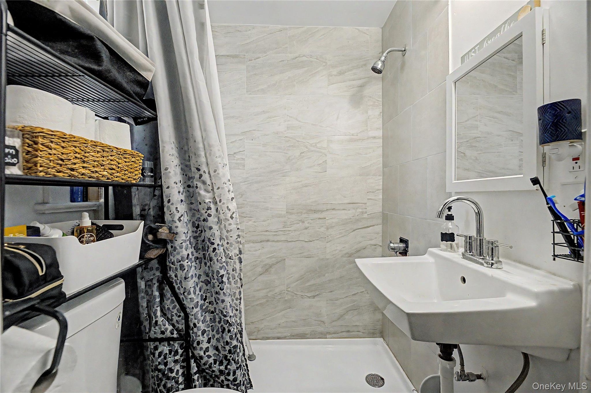 Bathroom featuring a wall-mounted sink, medicine cabinet with mirror, and shower with tiled walls