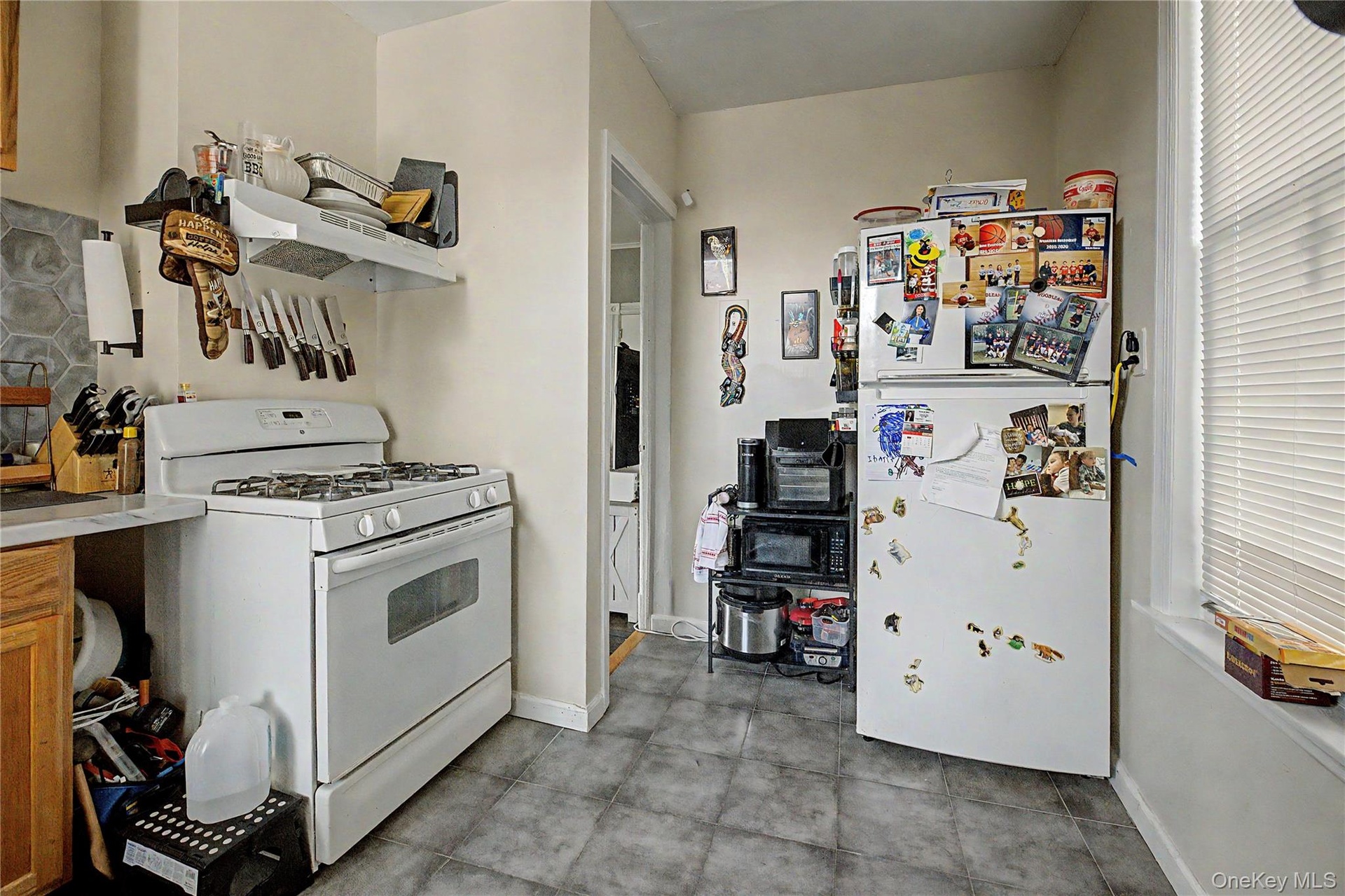 White walls with a window, stainless steel refrigerator, and stainless steel range
