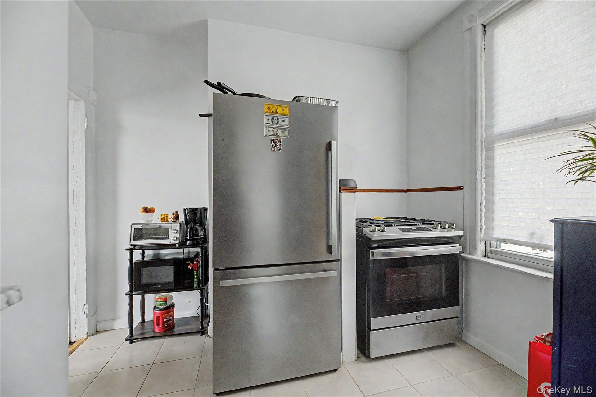 White walls with a window, stainless steel refrigerator, and stainless steel range