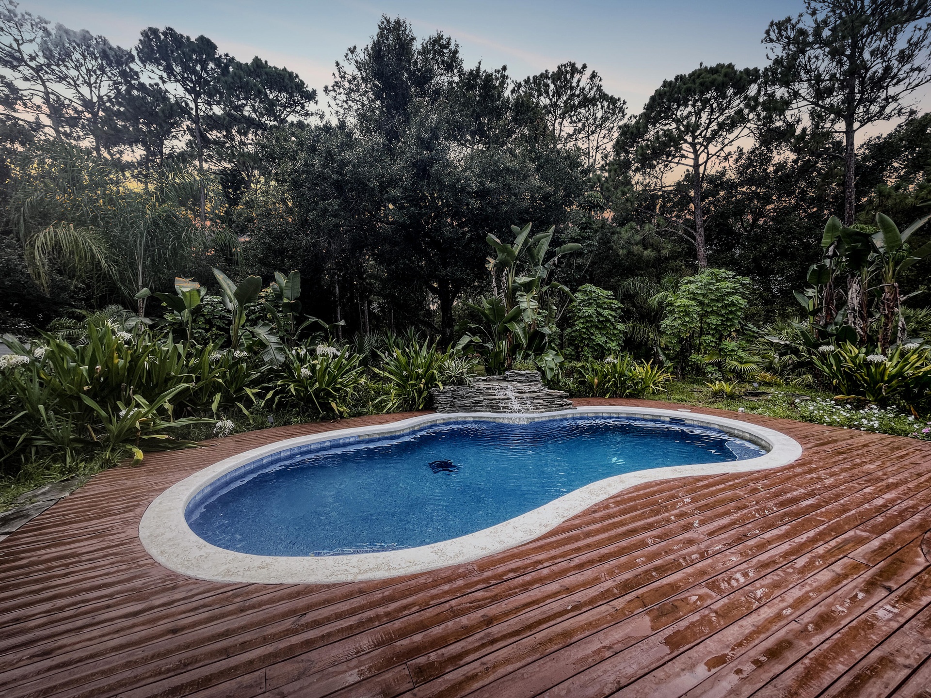 A custom wood pool deck around the free-form pool with a soothing waterfall