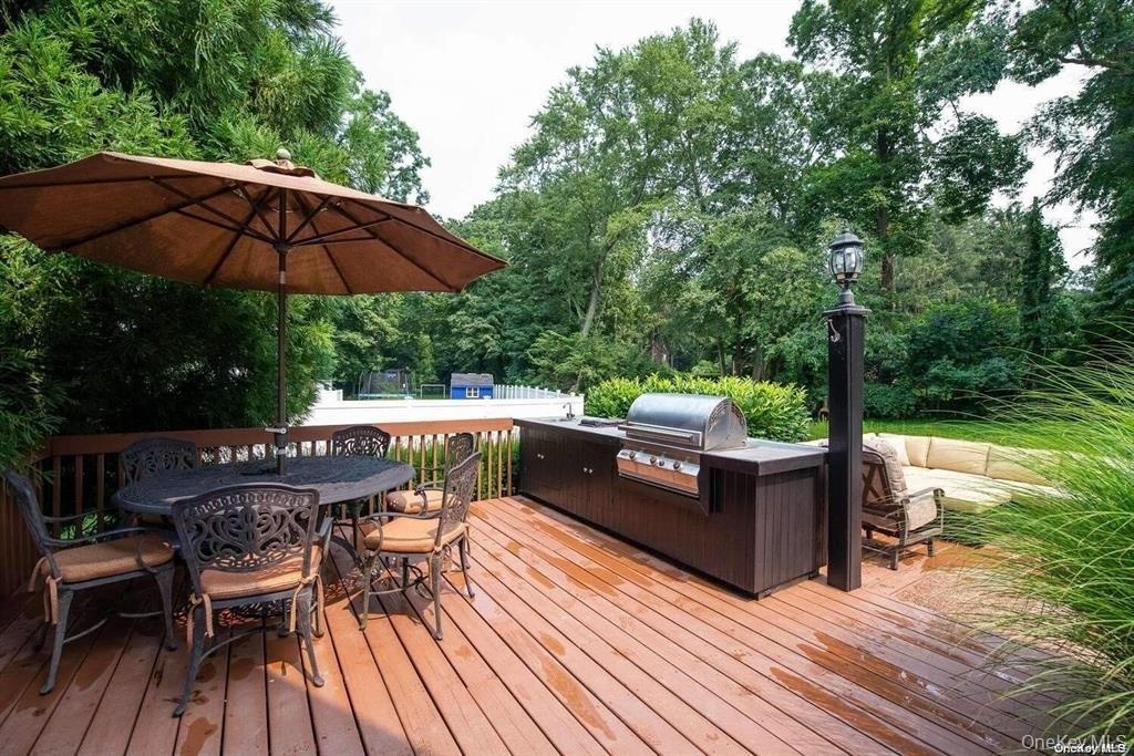 Wooden terrace featuring outdoor dining area and exterior kitchen