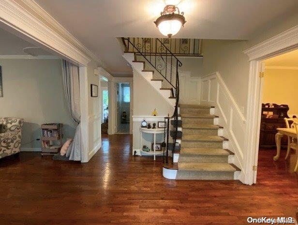 Stairs with crown molding and wood finished floors