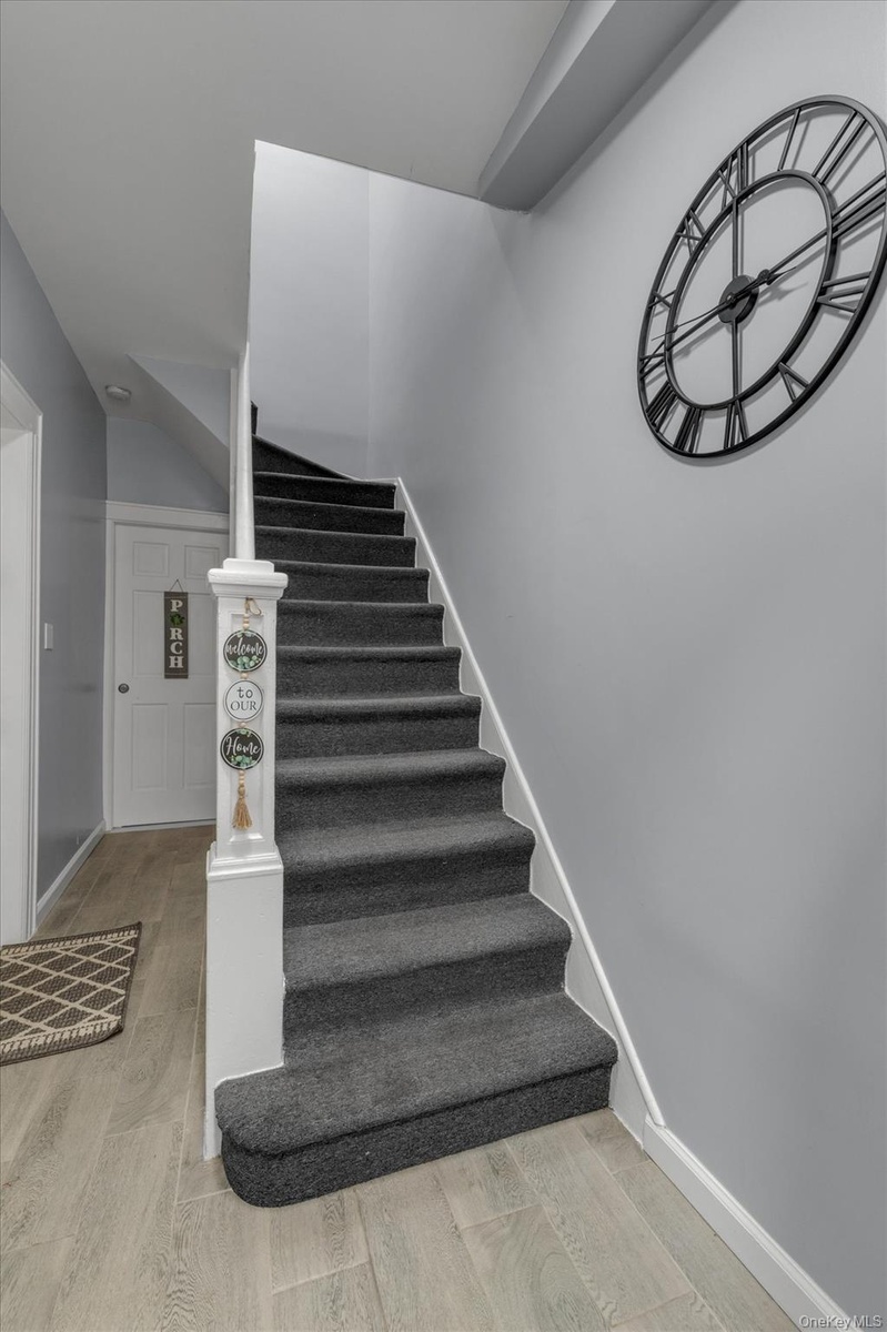 Elegant staircase featuring charcoal gray carpeted treads with white trim, ornamental newel post, and chrome handrail.