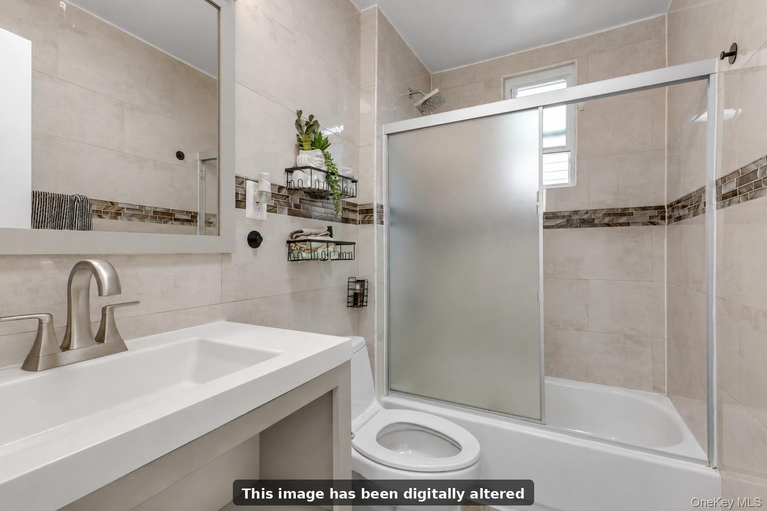 Bathroom featuring a shower-tub combination with sliding frosted glass doors, a vanity with an integrated sink, and tiled walls with a mosaic accent b