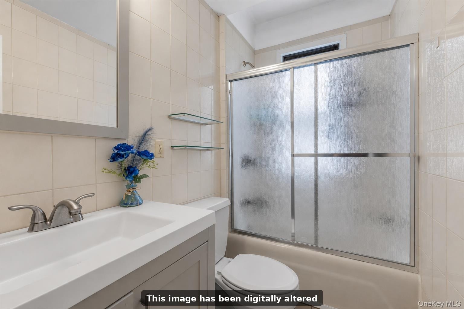 Bathroom featuring a neutral tile shower with sliding glass doors, a vanity with an integrated sink, a framed mirror, and wall-mounted glass shelving.