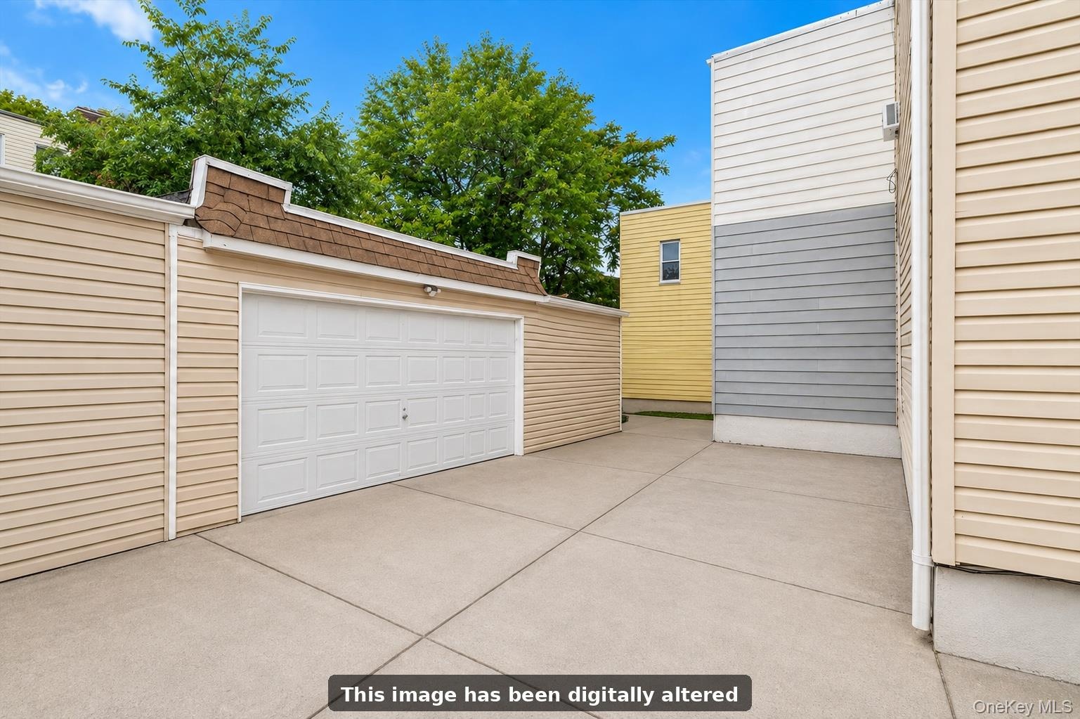 Concrete driveway leading to a detached garage with a paneled door.