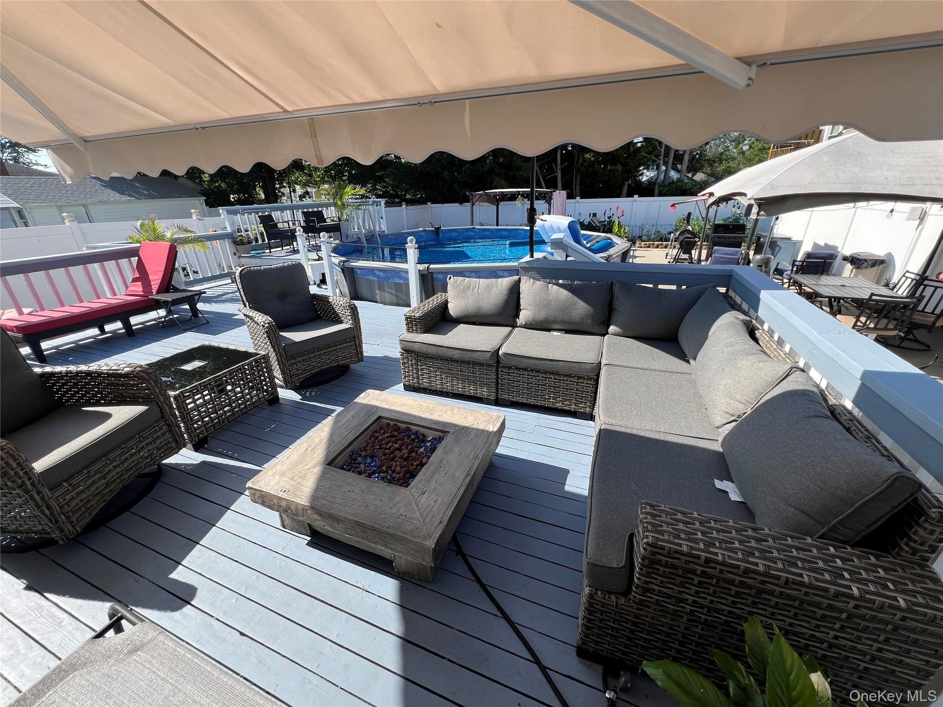 Expansive outdoor deck with a retractable awning, fire pit, and privacy fencing