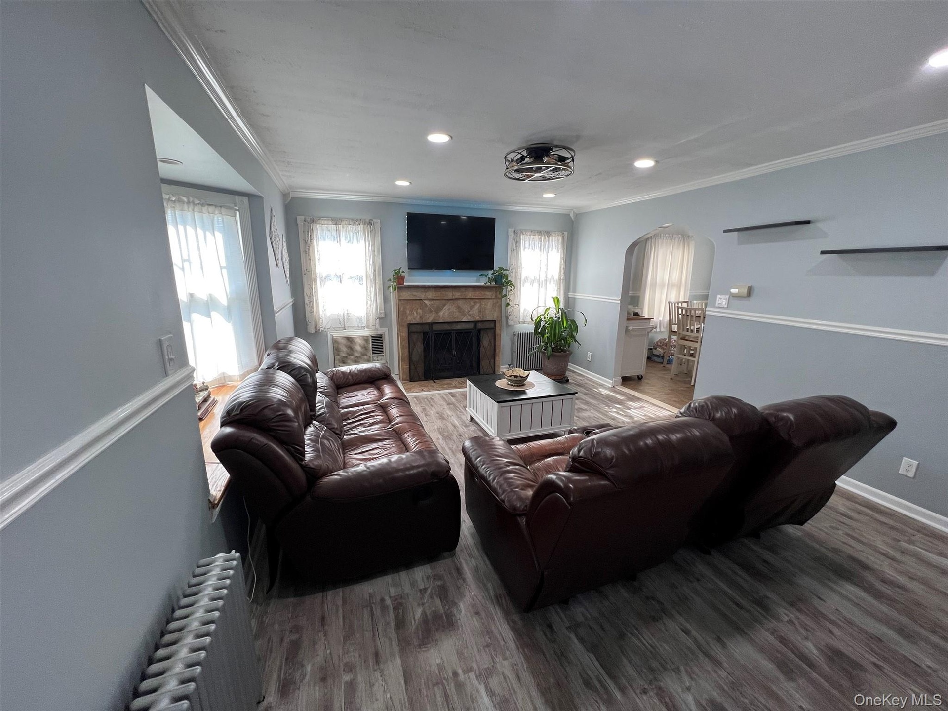 Bright, open living room anchored by a fireplace with stone surround and wood mantel, centered beneath a wall-mounted flat-screen television