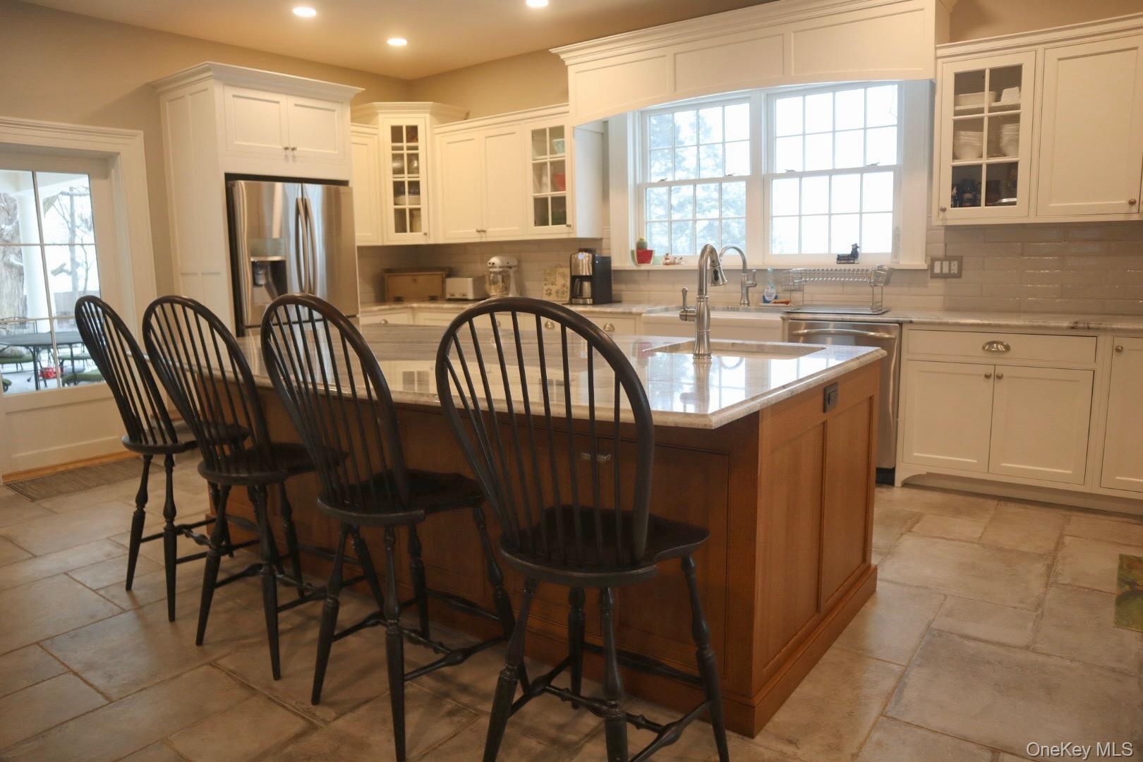 Kitchen featuring sink, a breakfast bar area, a center island with sink, appliances with stainless steel finishes, and white cabinets