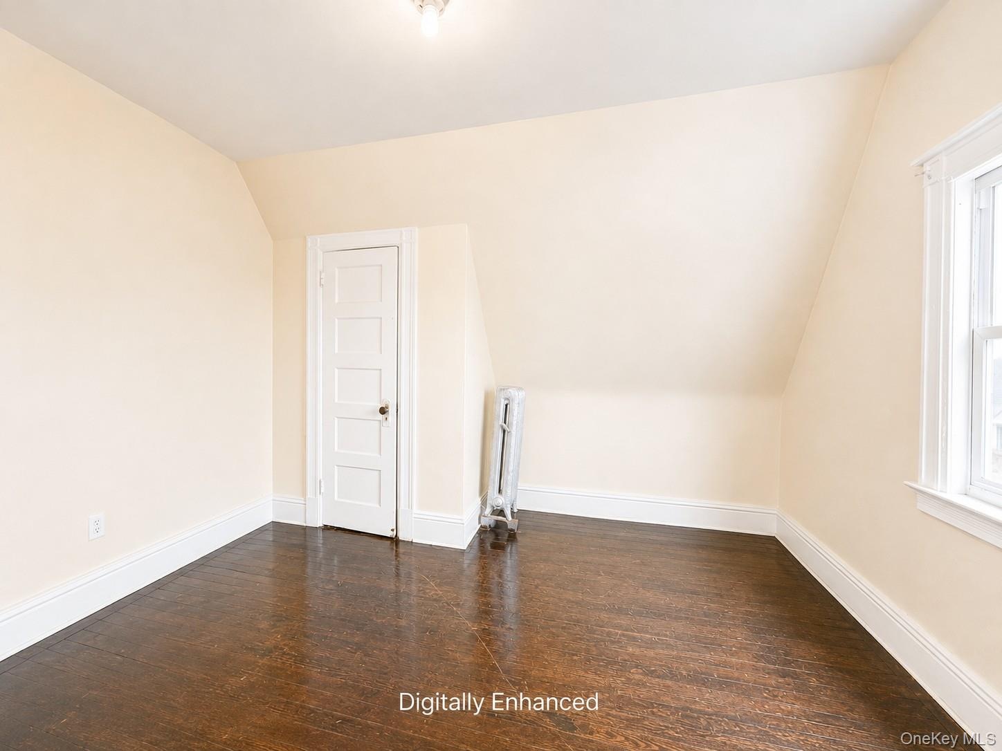 3rd fl Sloped ceiling room featuring wood-finish flooring, a white paneled door, and a single window