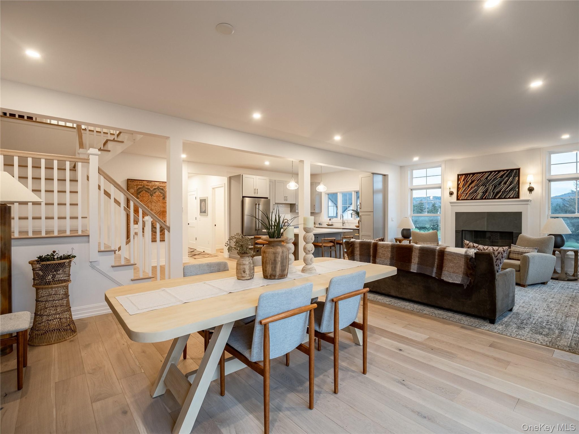Dining area featuring a tile fireplace, stairs, light wood finished floors, and recessed lighting