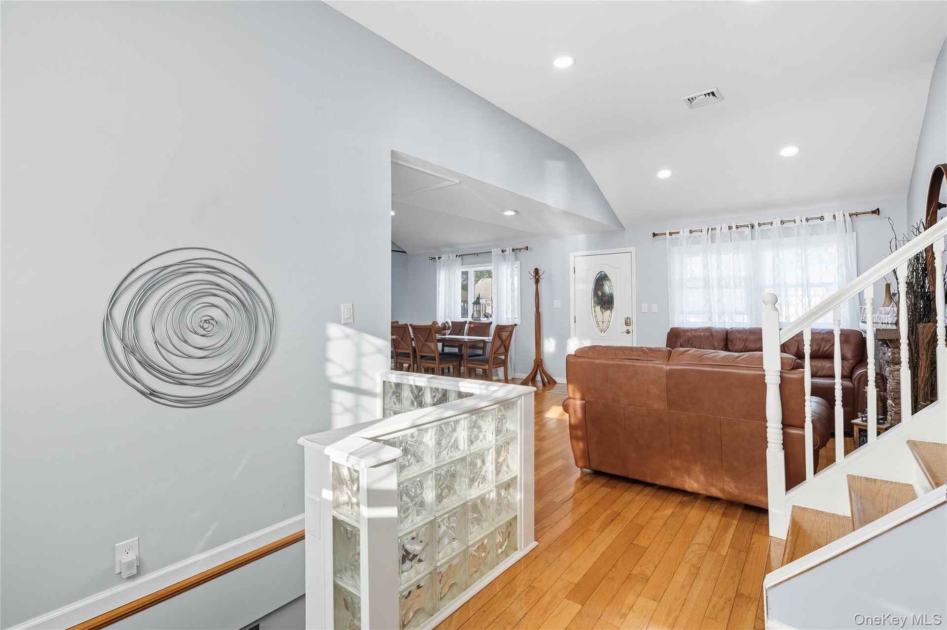 Living room featuring light wood-type flooring, vaulted ceiling, recessed lighting, and stairs