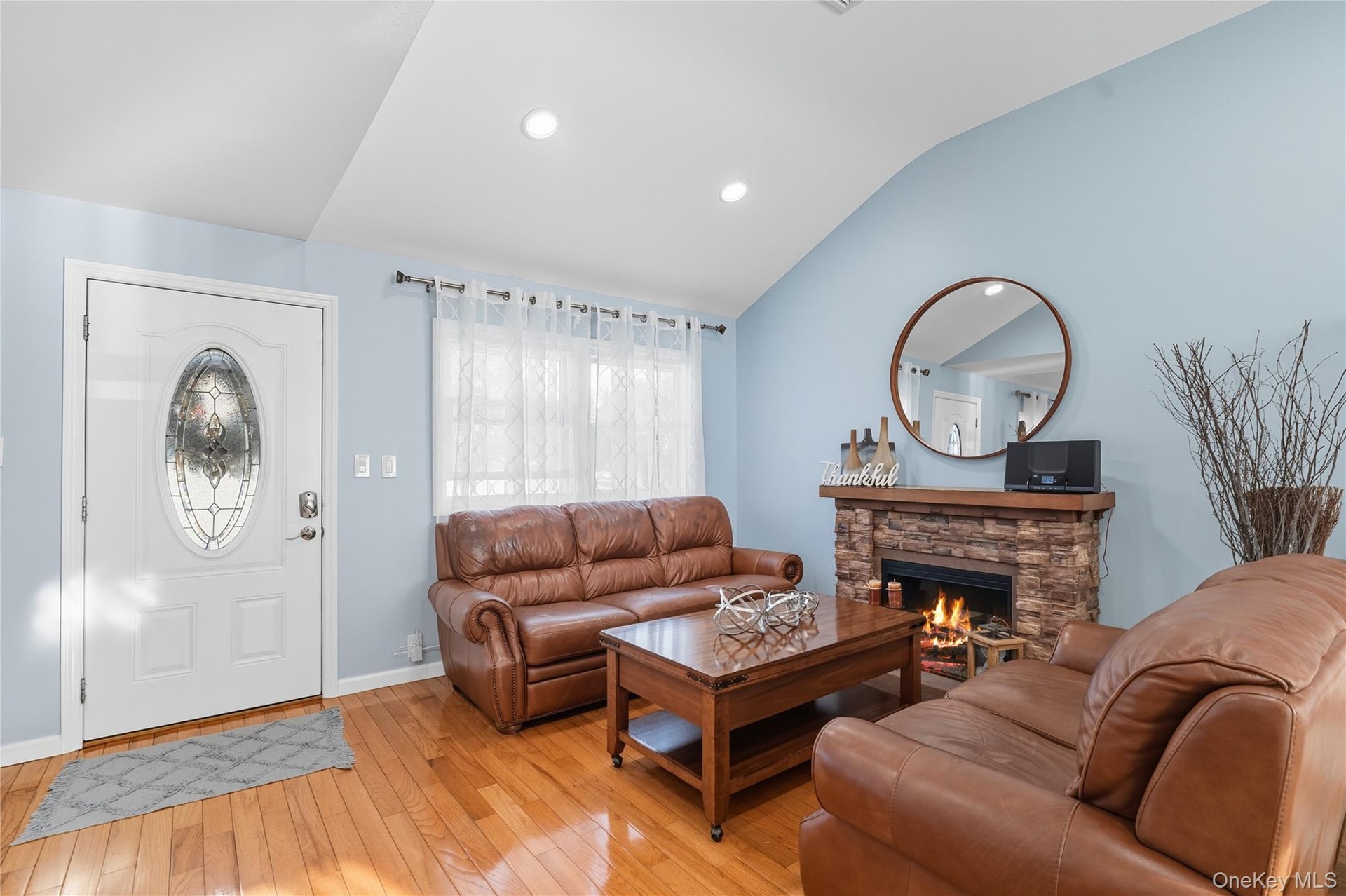 Living area with lofted ceiling, hardwood / wood-style floors, a fireplace, and recessed lighting