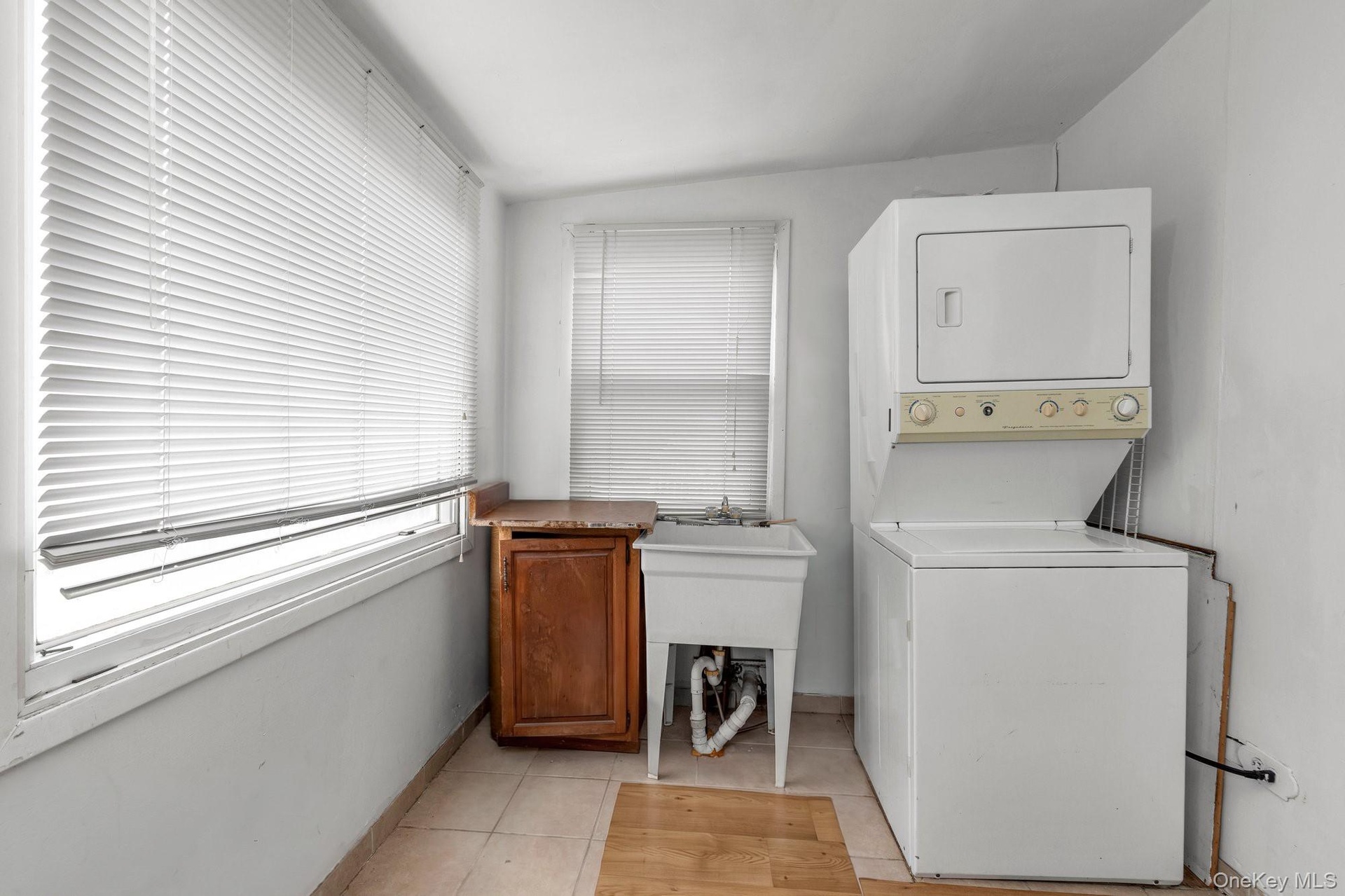 Laundry area with a utility sink, wood-finish cabinetry, and tiled flooring