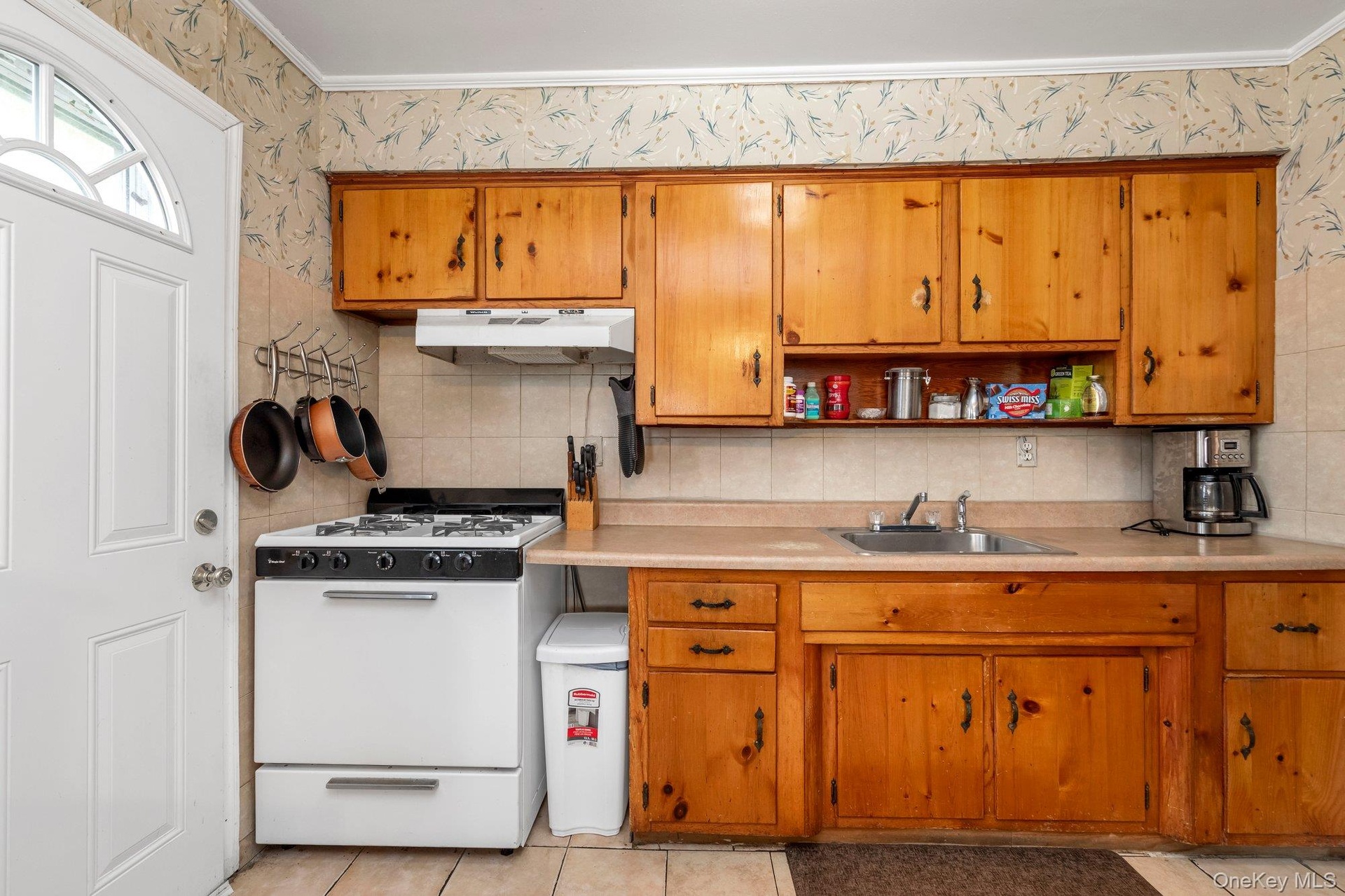 Wood-finish cabinetry paired with a white gas range, stainless steel sink, and light-toned countertops