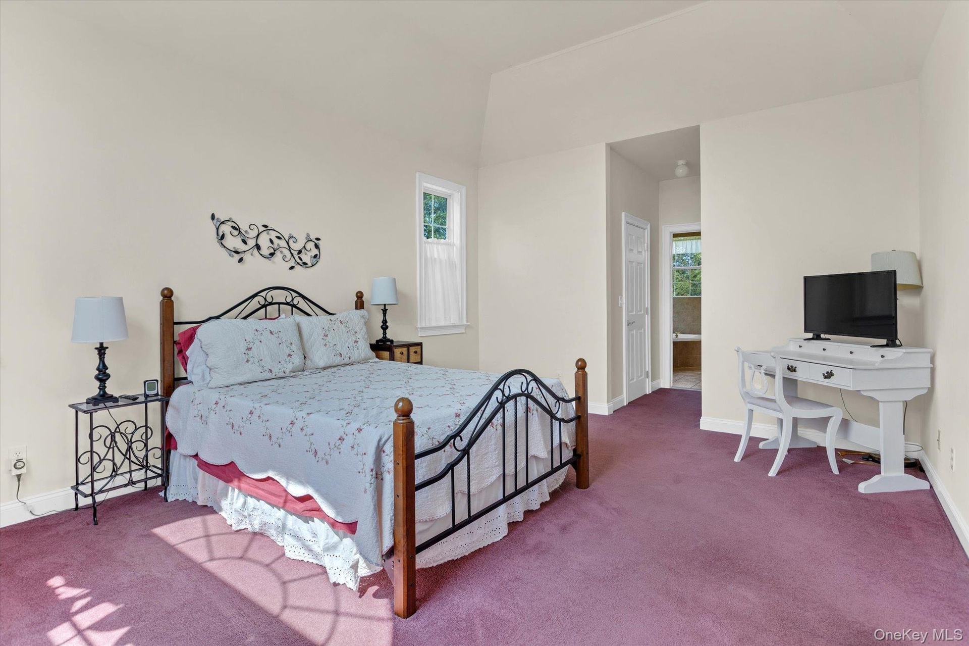 Vaulted ceiling, wall-to-wall carpeting, and an arched doorway