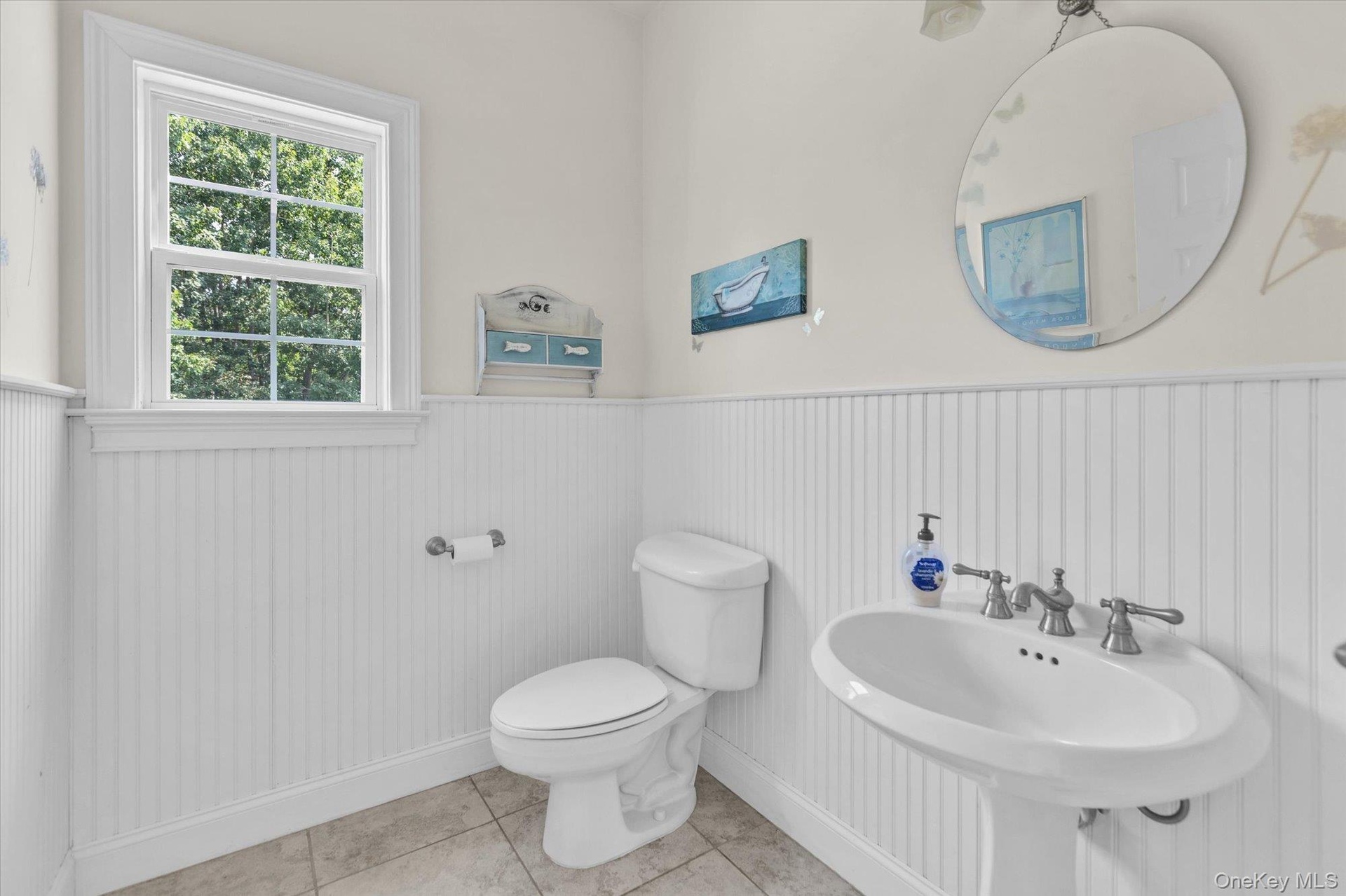 White beadboard paneling, pedestal sink, chrome faucet, and tiled flooring