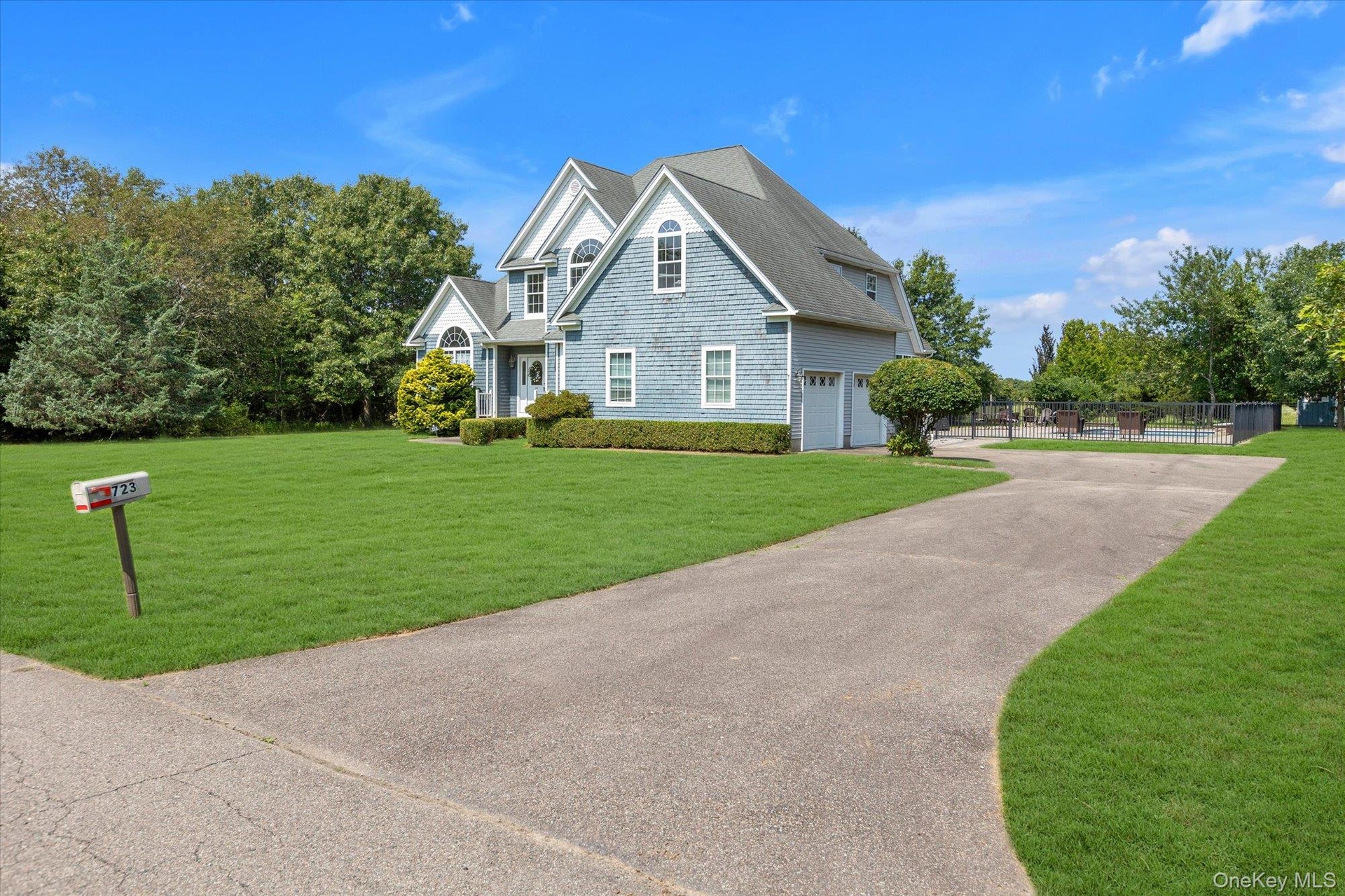 Shingle-sided exterior with multiple gables, an attached two-car garage, a paved driveway, and a spacious lawn