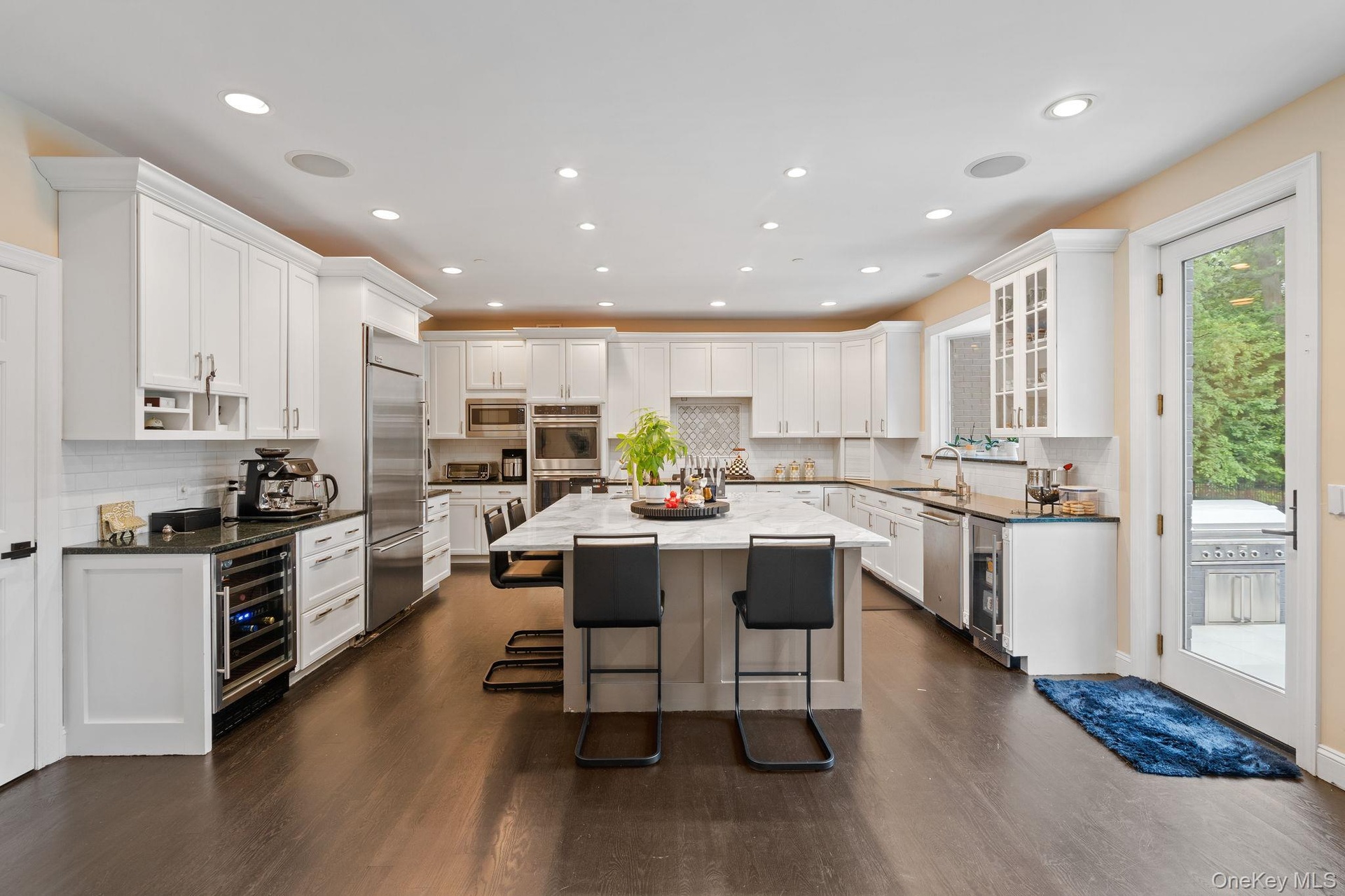 Kitchen featuring a kitchen breakfast bar, decorative backsplash, white cabinets, dark wood finished floors, and recessed lighting