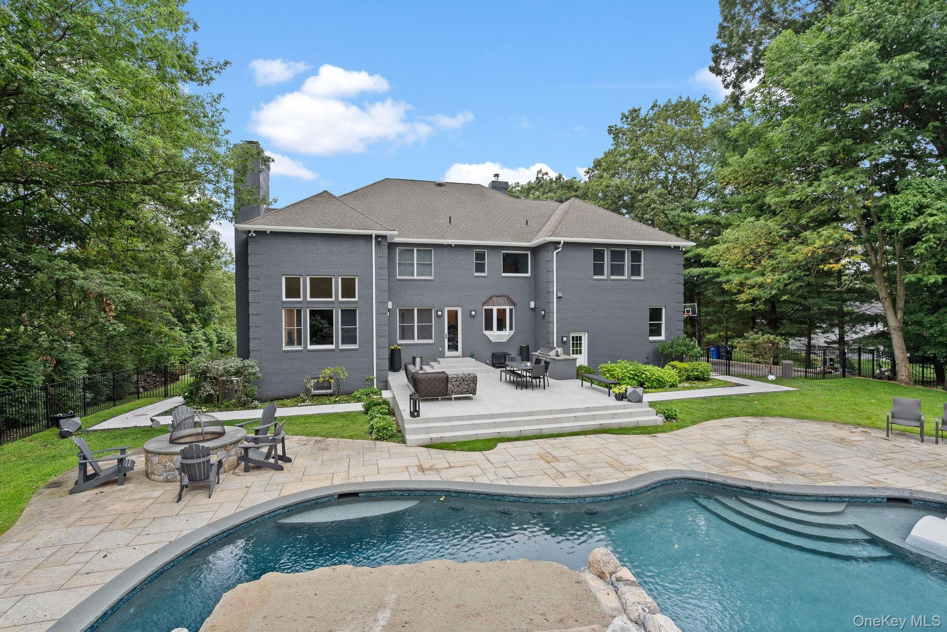 Back of property with an outdoor fire pit, a patio, a chimney, an outdoor pool, and roof with shingles