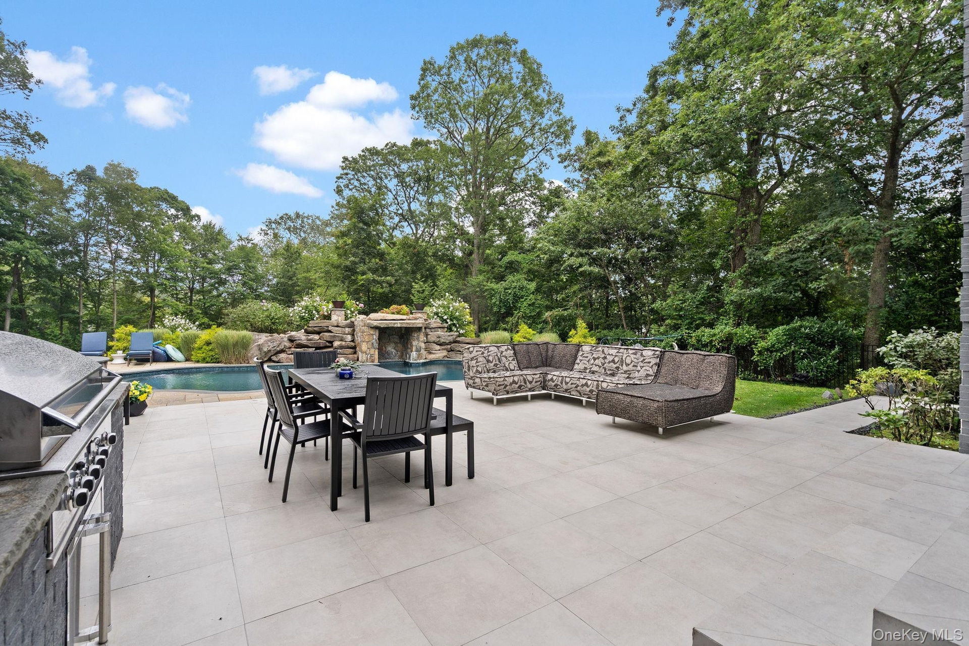 View of patio / terrace featuring an outdoor pool, outdoor dining space, view of wooded area, area for grilling, and an outdoor living space