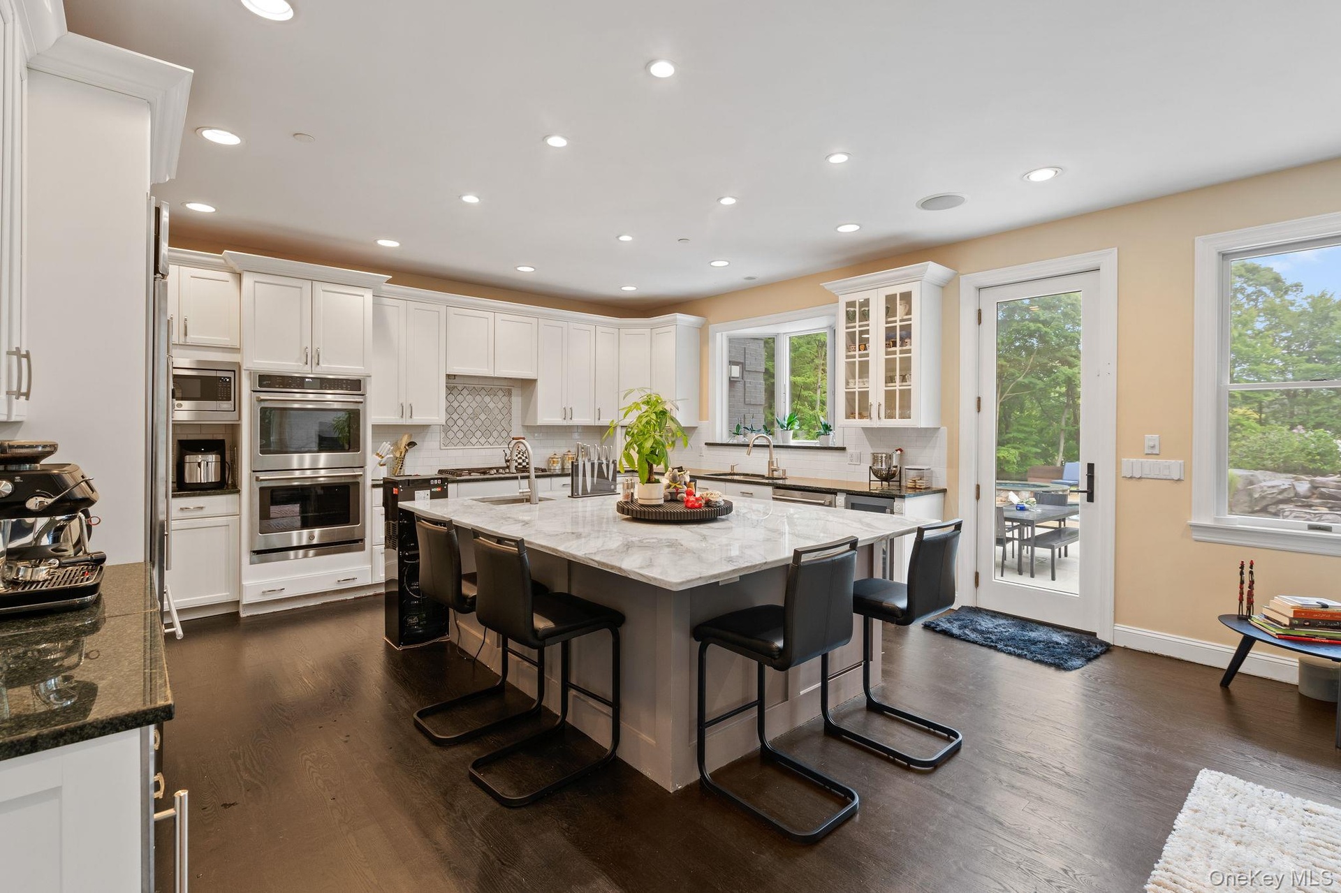 Kitchen featuring tasteful backsplash, light stone counters, a breakfast bar, an island with sink, and white cabinets