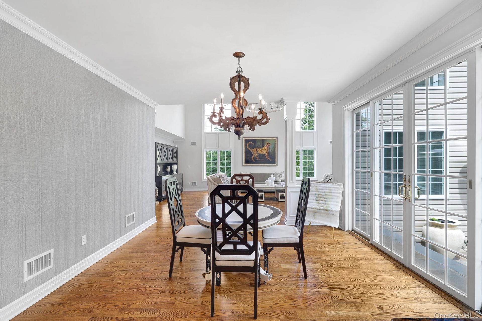 Hardwood flooring throughout, elegant crown molding, double French doors with transom windows, and a chandelier light fixture and access to outdoor pa