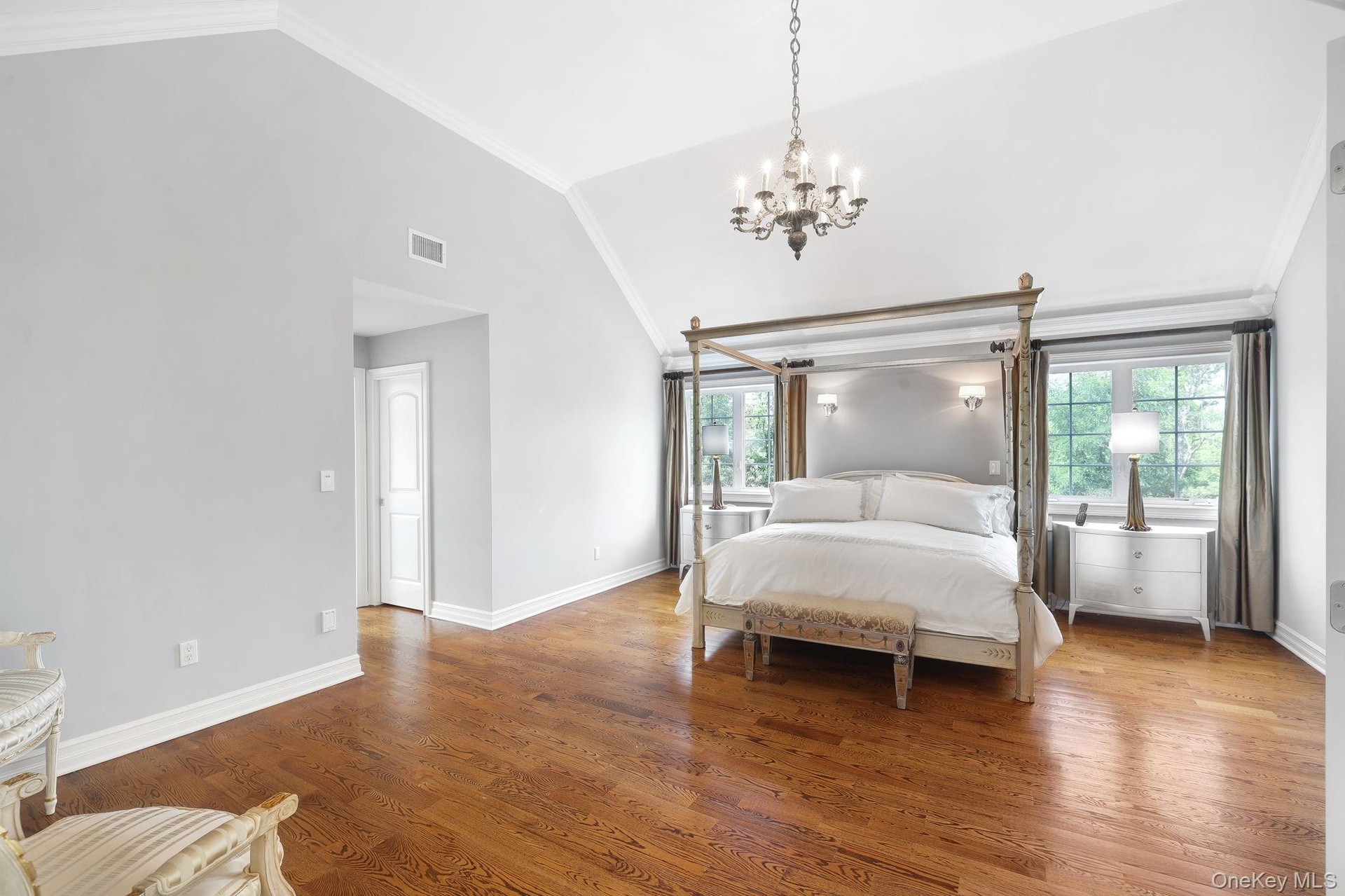 Oversized with vaulted ceiling with crown molding, wood-finish flooring, multiple windows, and a chandelier