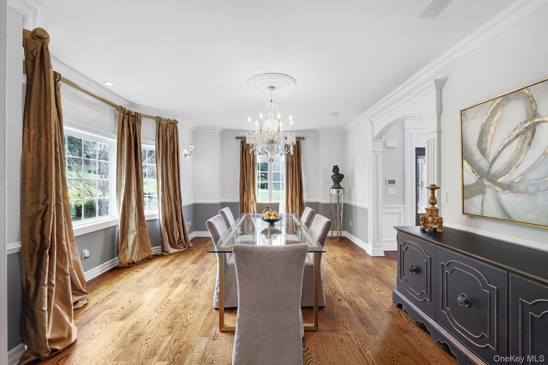Hardwood flooring, arched doorway, elegant chandelier, crown molding, and wainscoting