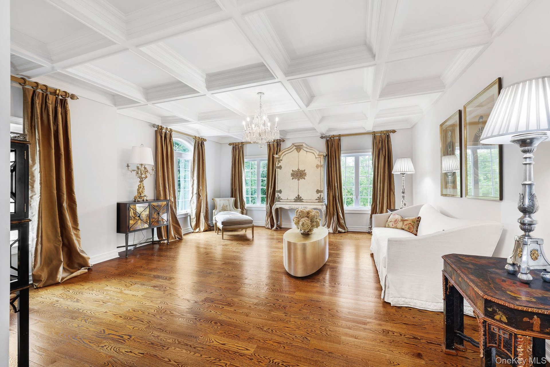 Coffered ceiling with a crystal chandelier, wood-finish flooring, and multiple windows