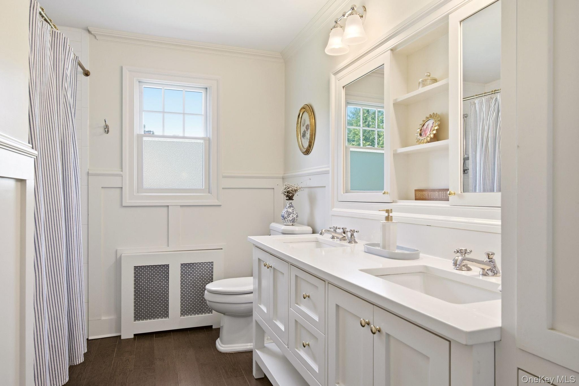 Gorgeous Hallway Bathroom with double vanity, built in shelving, wainscotting and tub.