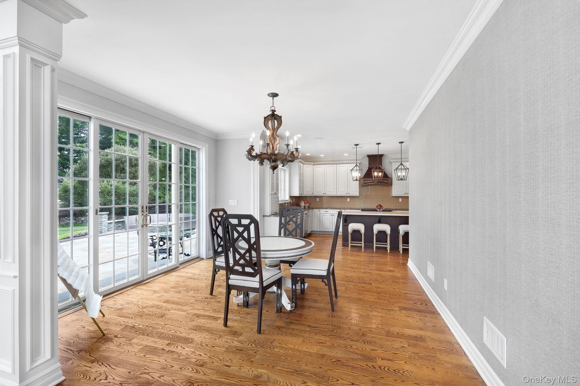 Hardwood flooring, crown molding, wall paneling, French doors, and a decorative chandelier and access to outdoor patio