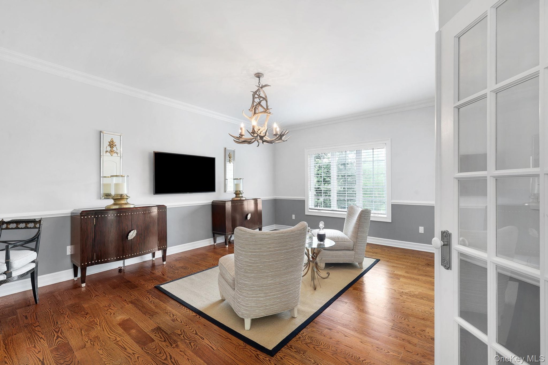 Hardwood flooring, crown molding, double doors and custom decorative antler chandelier