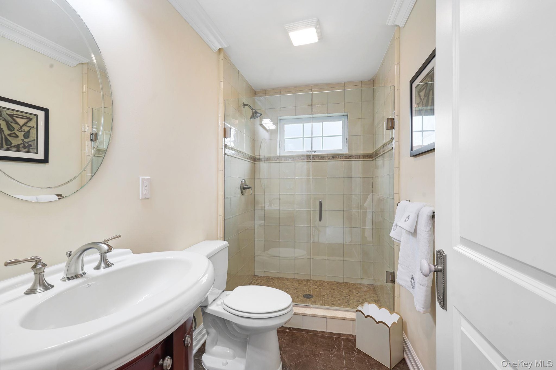 Upstairs elegant bathroom featuring a curved pedestal sink with chrome fixtures, ceramic tile shower enclosure with glass doors, white subway tile sur