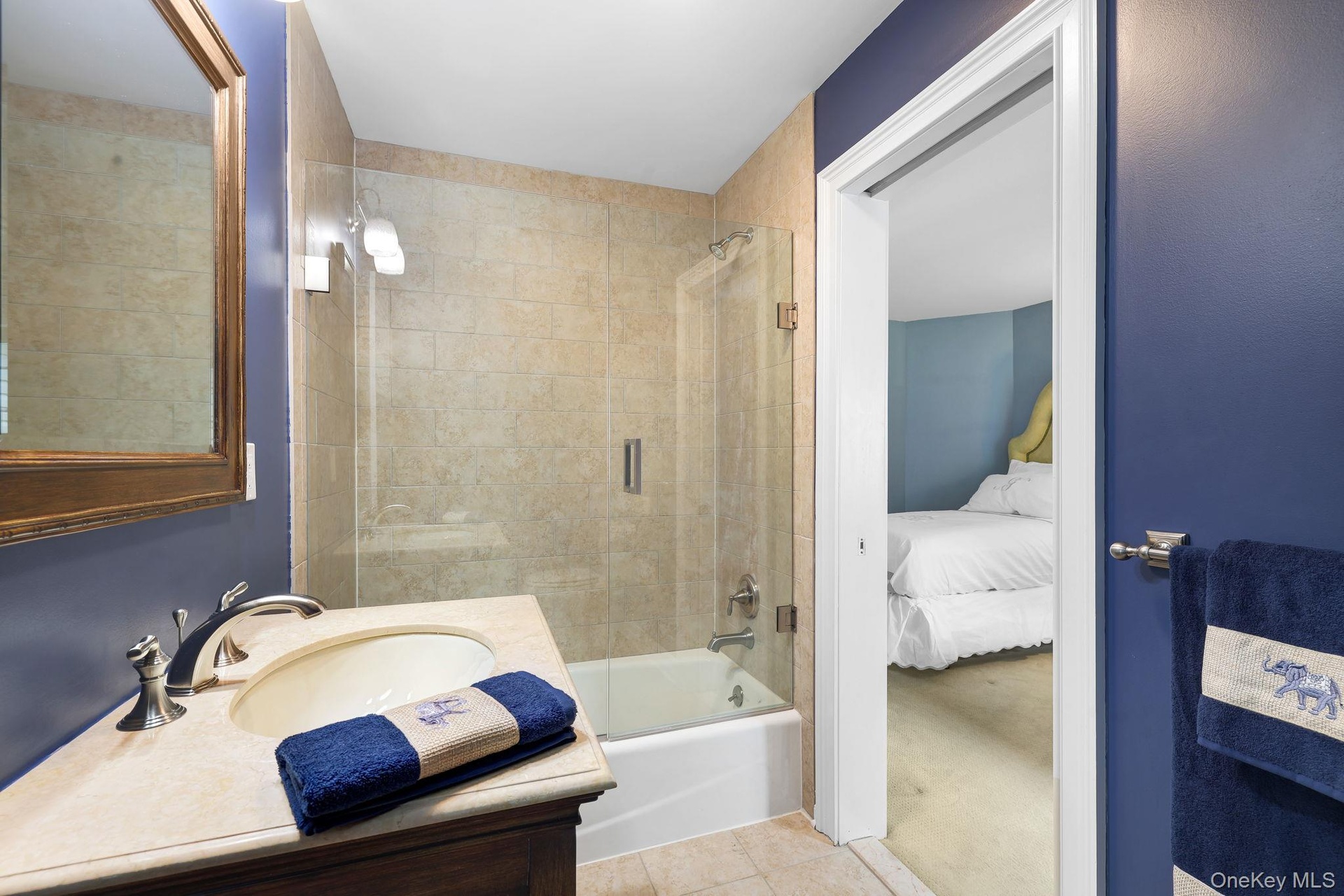 Jack and Jill bathroom featuring a single vanity with an integrated sink, polished chrome faucet, a framed mirror, and a tiled shower-tub combination 