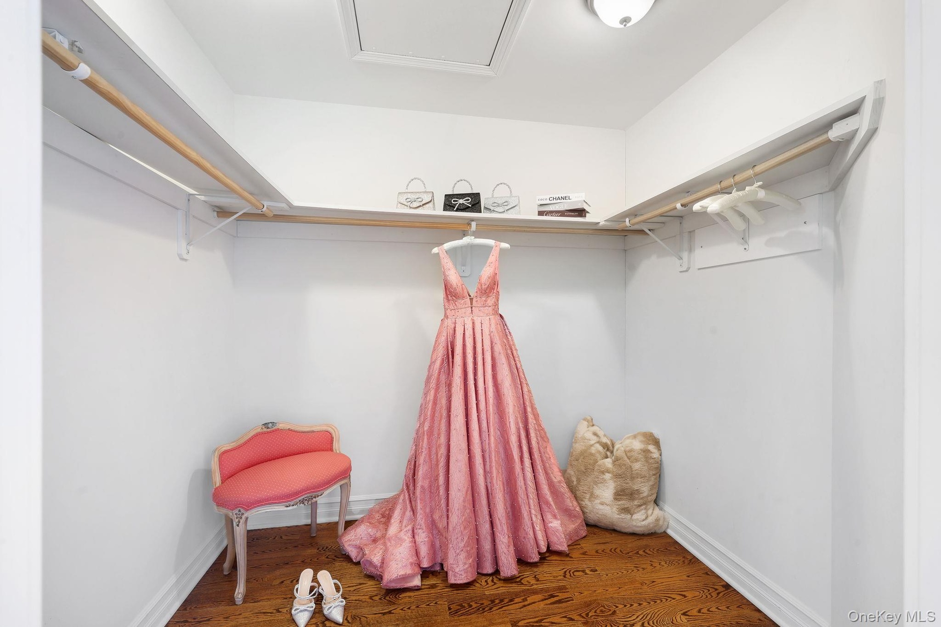 One of two oversized primary walk-in closets ,hardwood-finish flooring, built-in shelving, and hanging rods