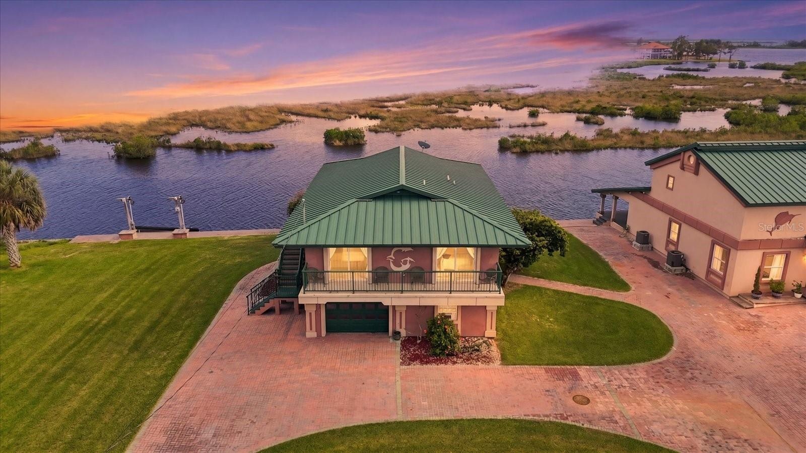 Twilight aerial showcasing the waterfront residence and natural coastal setting.
