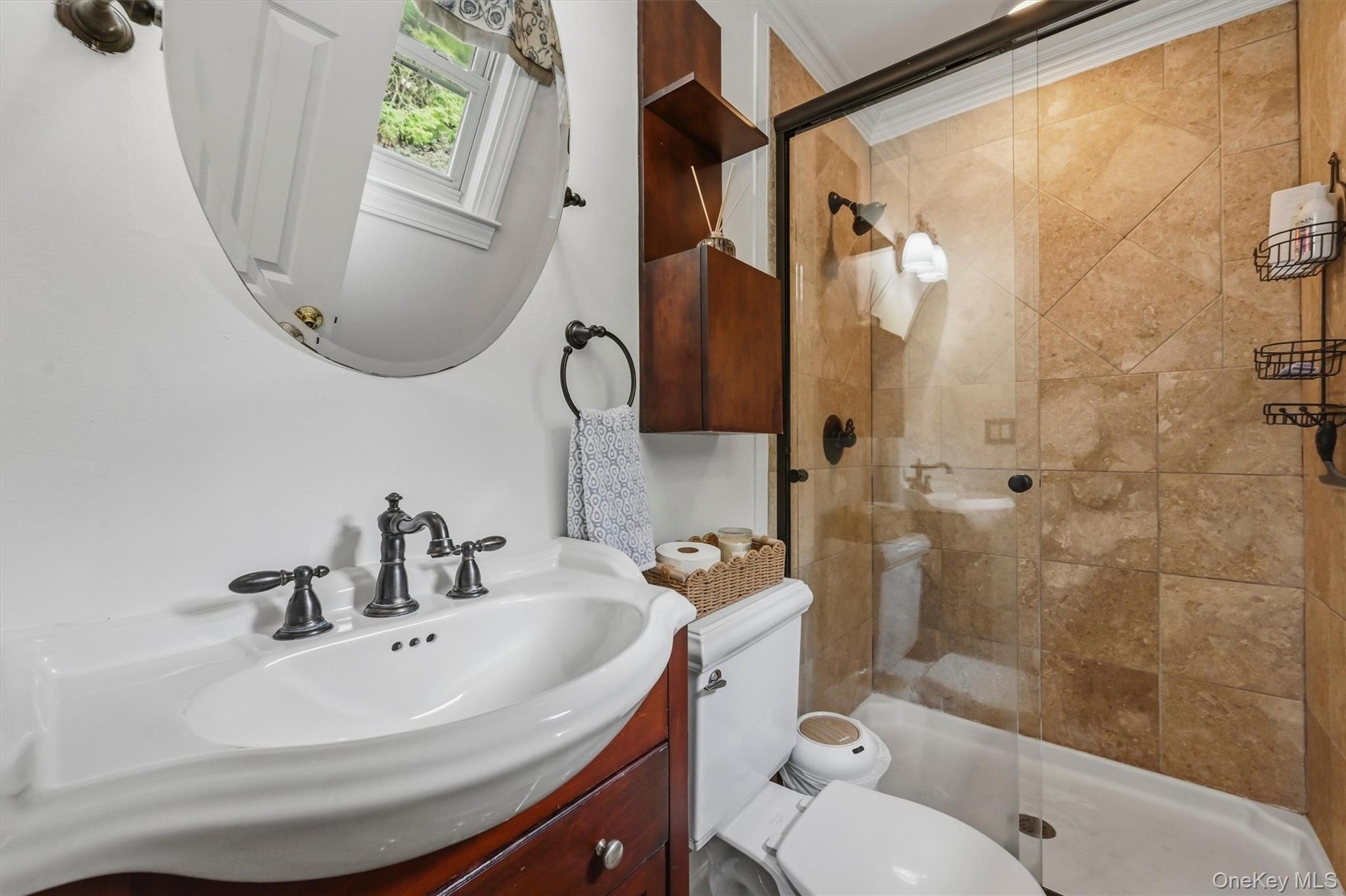 The primary bathroom has a tiled shower. matte black fixtures, glass door and crown molding.