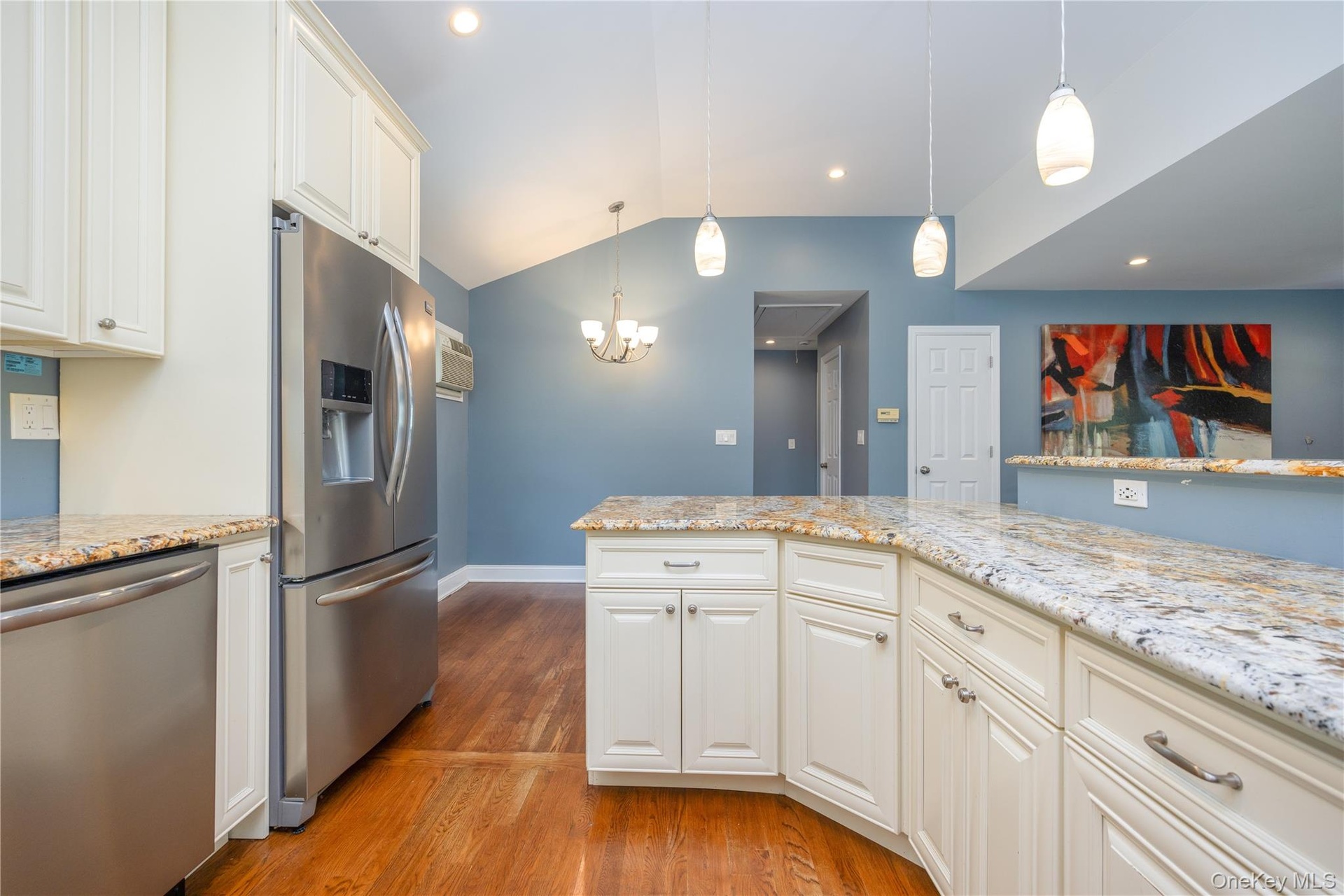 Vaulted ceiling, recessed lighting, wood-finish flooring, white cabinetry, and stainless steel appliances