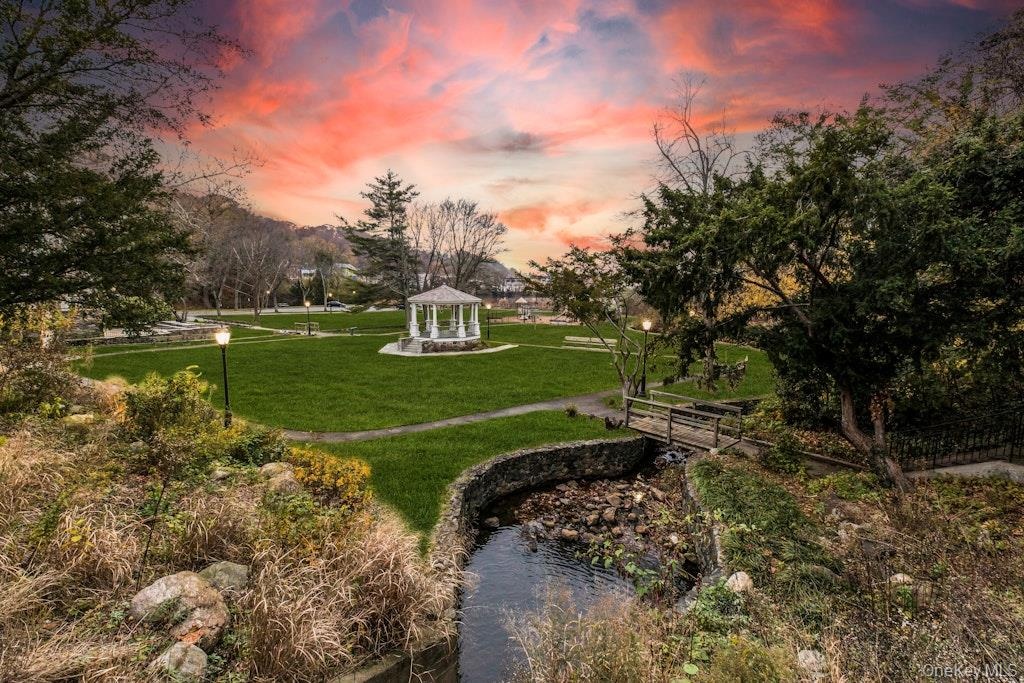 Surrounding community featuring a gazebo, a lawn, and view of wooded area