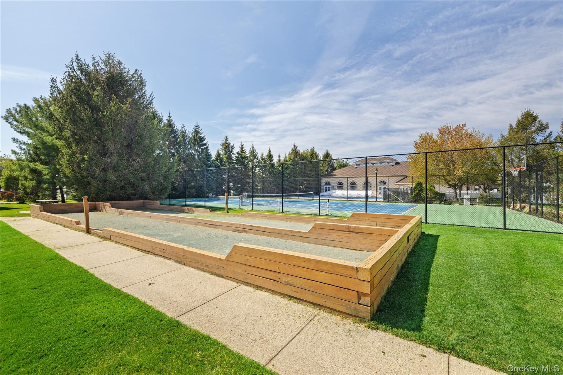 Bocce ball court with wood-finish perimeter, hardscaped pathway, and manicured lawn